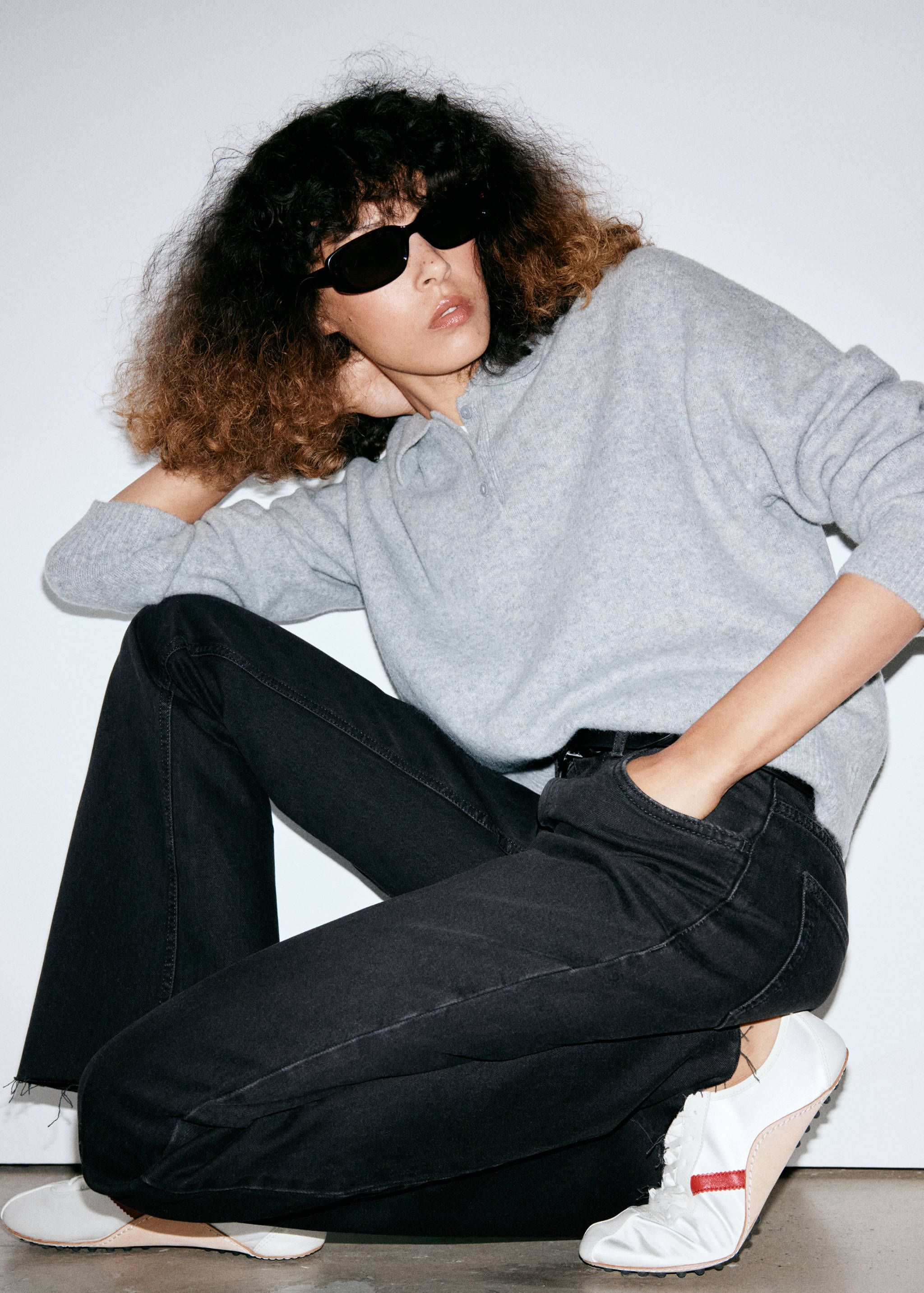 Black denim jeans with a relaxed fit and flared legs, worn with a grey sweater.