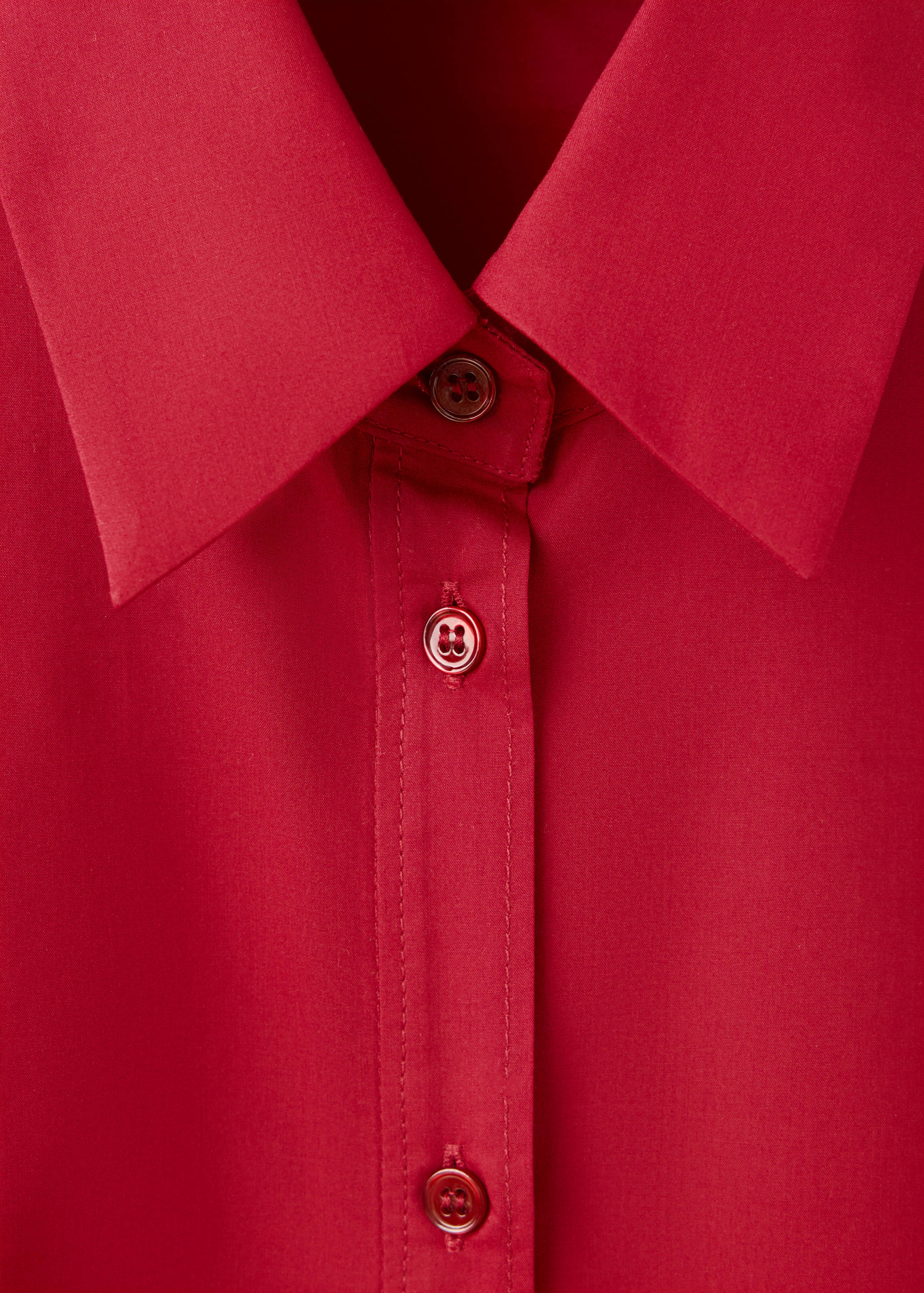 Close-up of a red shirt collar and button placket.