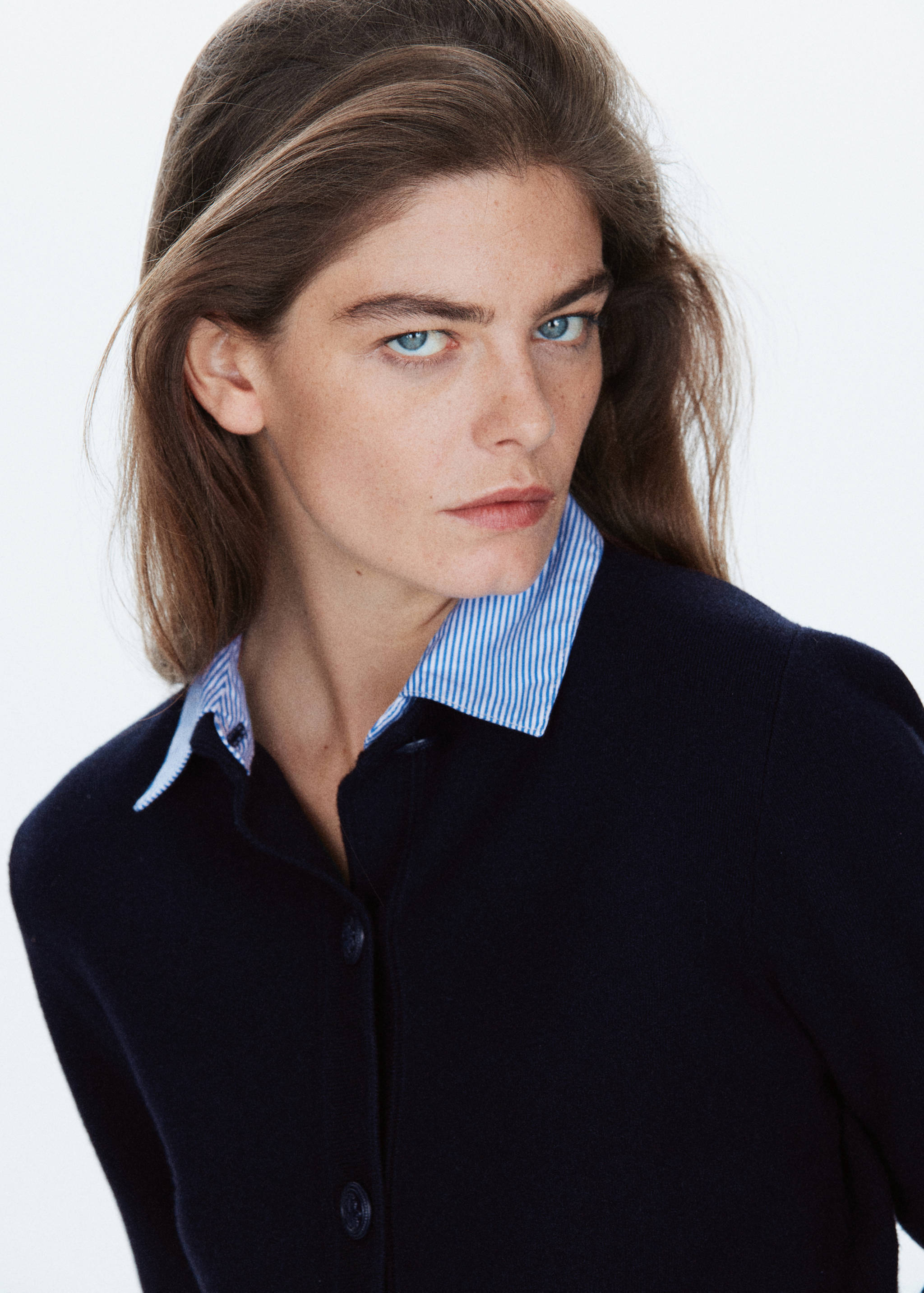 Close-up of a navy blue jacket with a layered striped shirt collar.