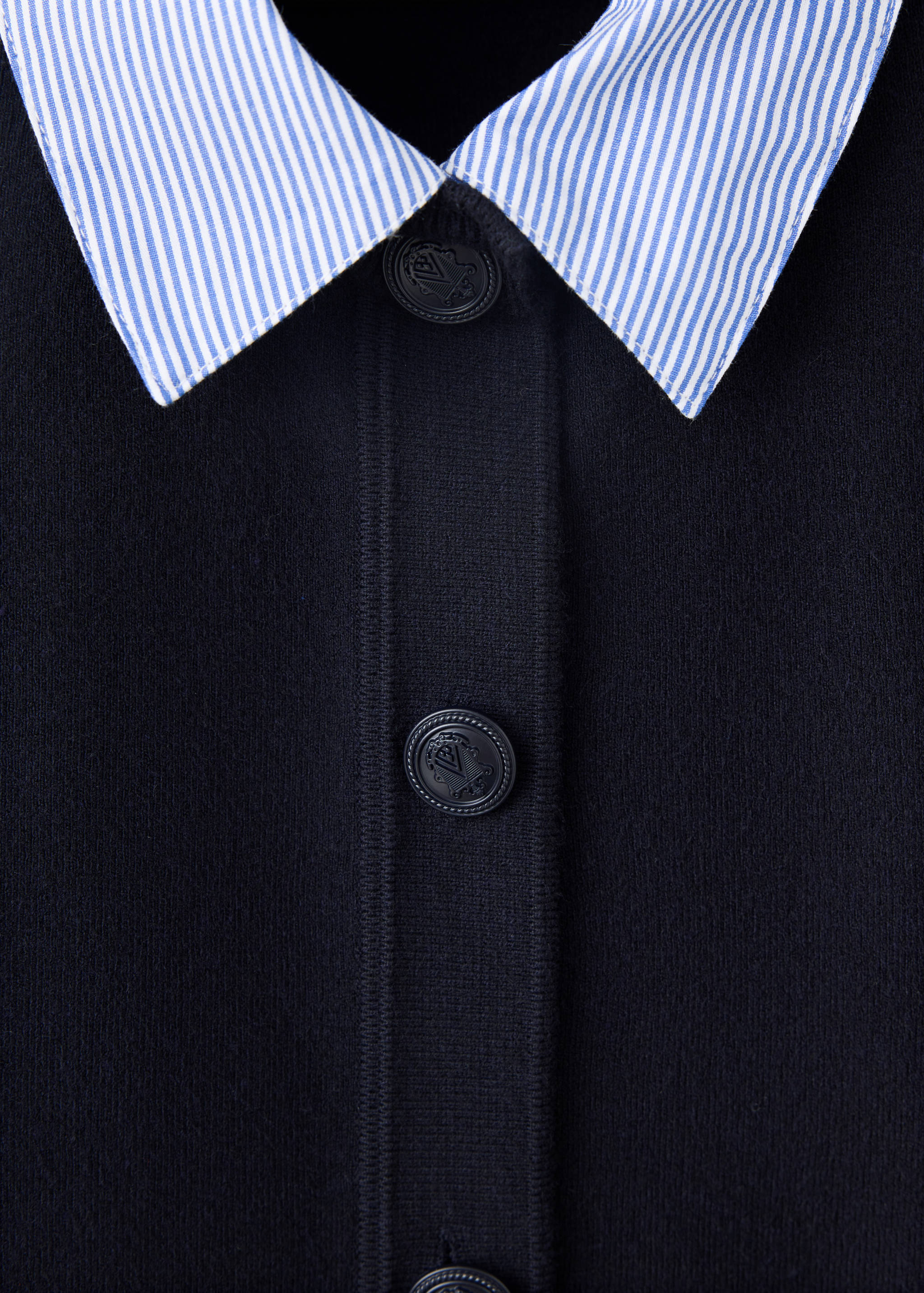 Navy blue cardigan jacket detail with a striped collar and embossed buttons.