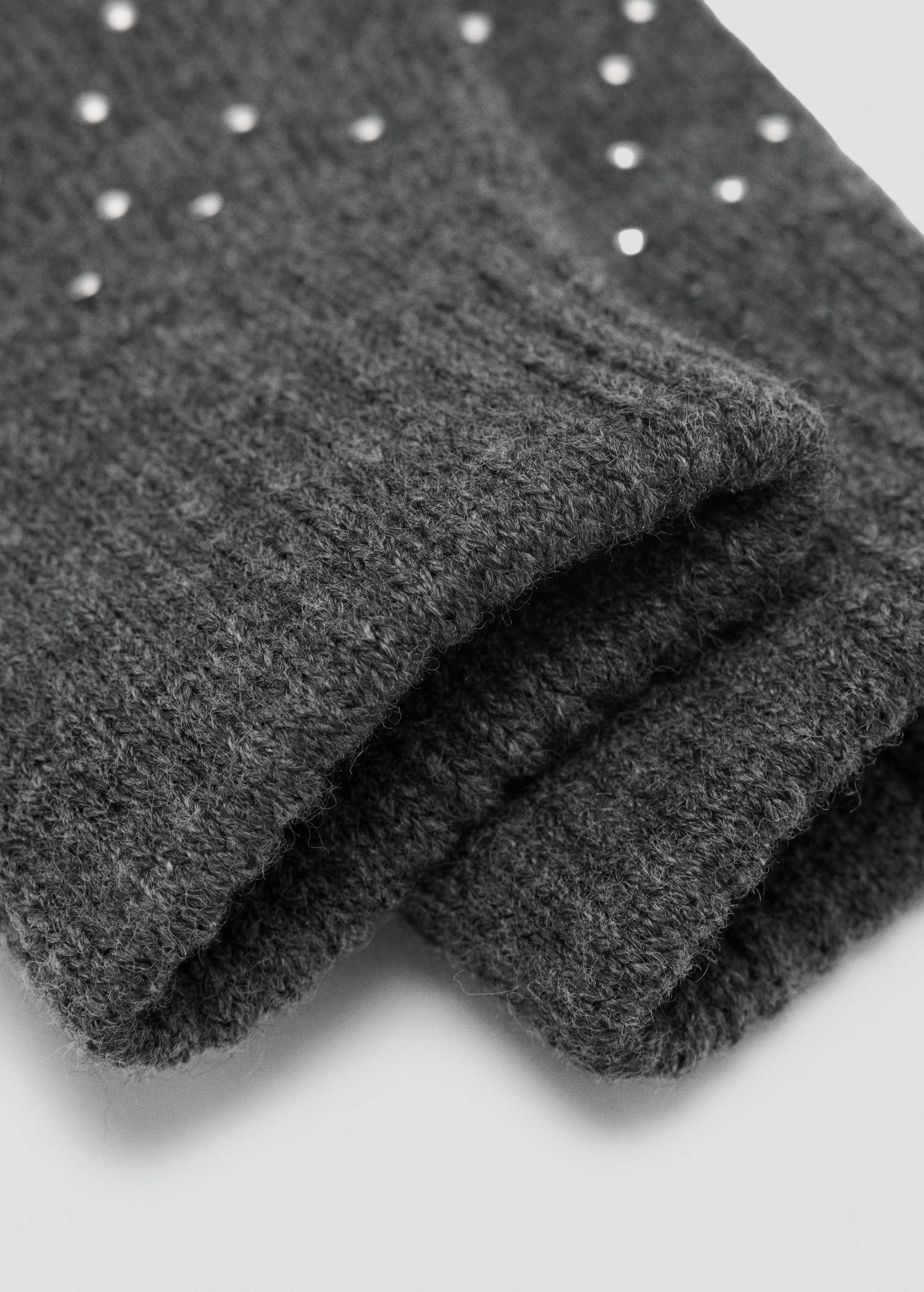 Dark grey knit gloves with ribbed cuffs and sparkling rhinestone details in a close-up still life.