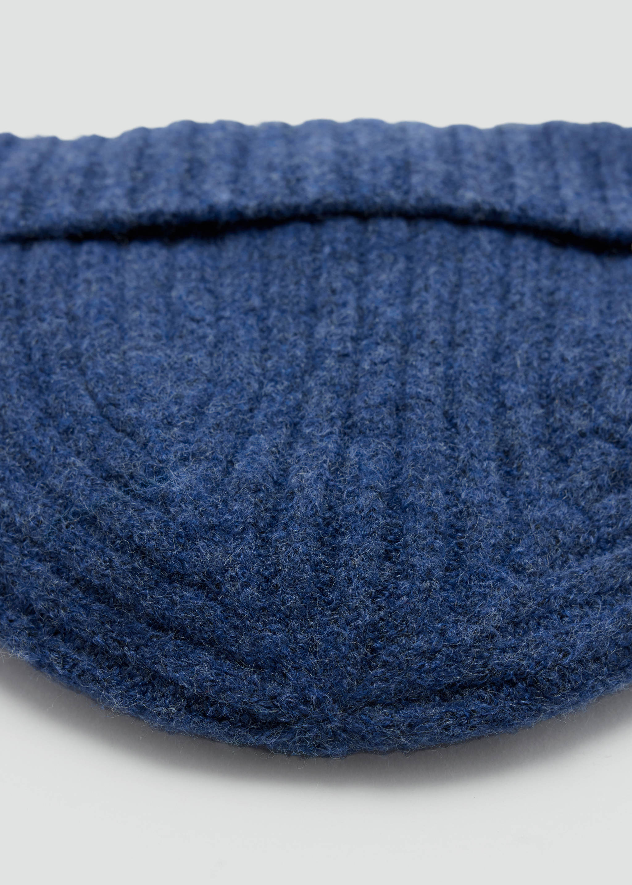 Close-up of a dark blue knitted hat with a ribbed texture and folded brim.