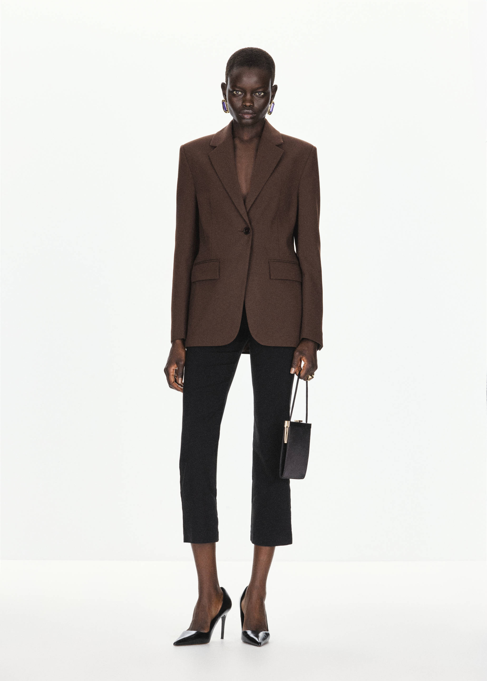 Brown tailored blazer with notched lapels and single-button closure, styled with black trousers.