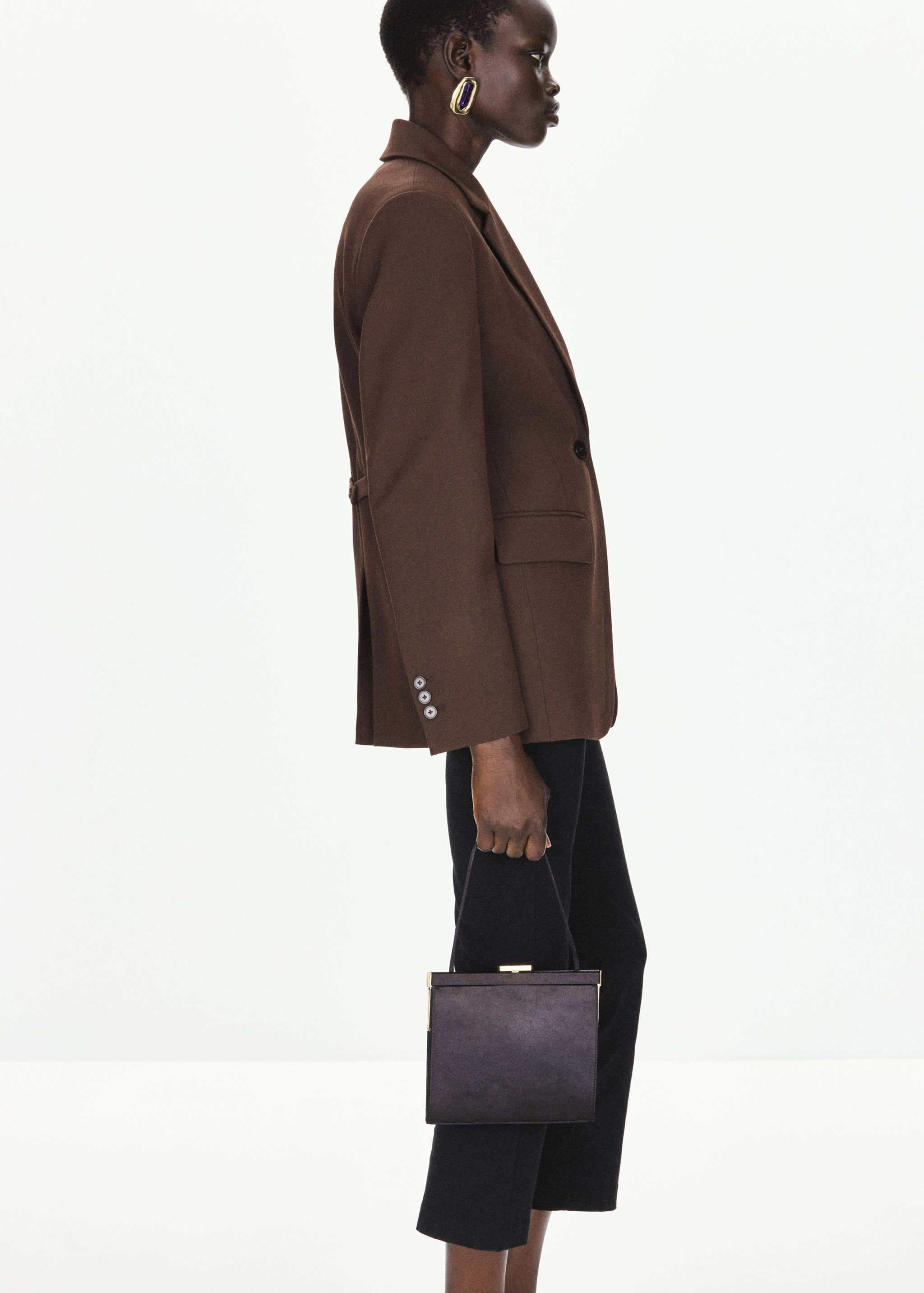 Brown tailored blazer with notched lapels and flap pockets, side view.