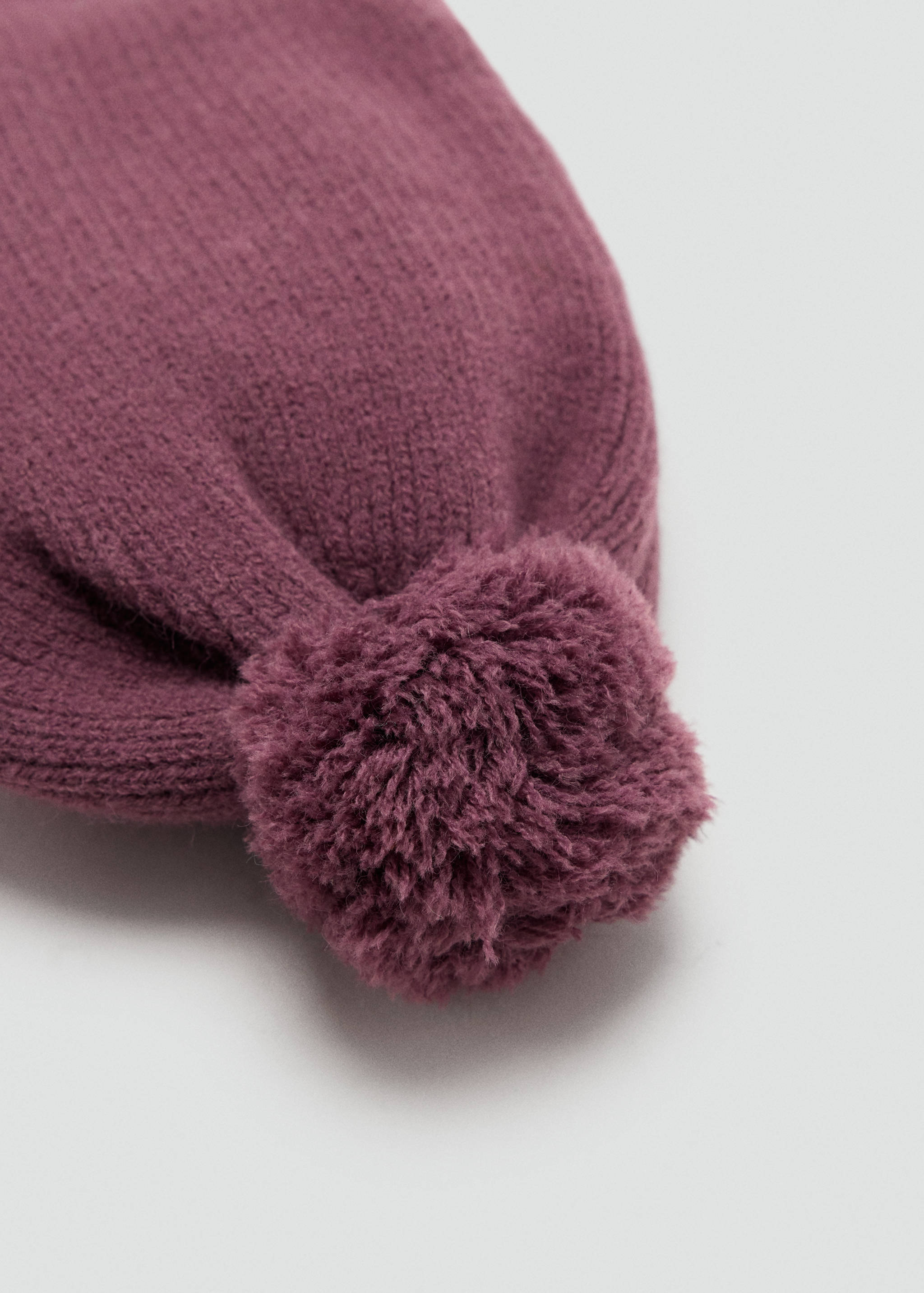 Plum knit beanie hat with a matching pom-pom.