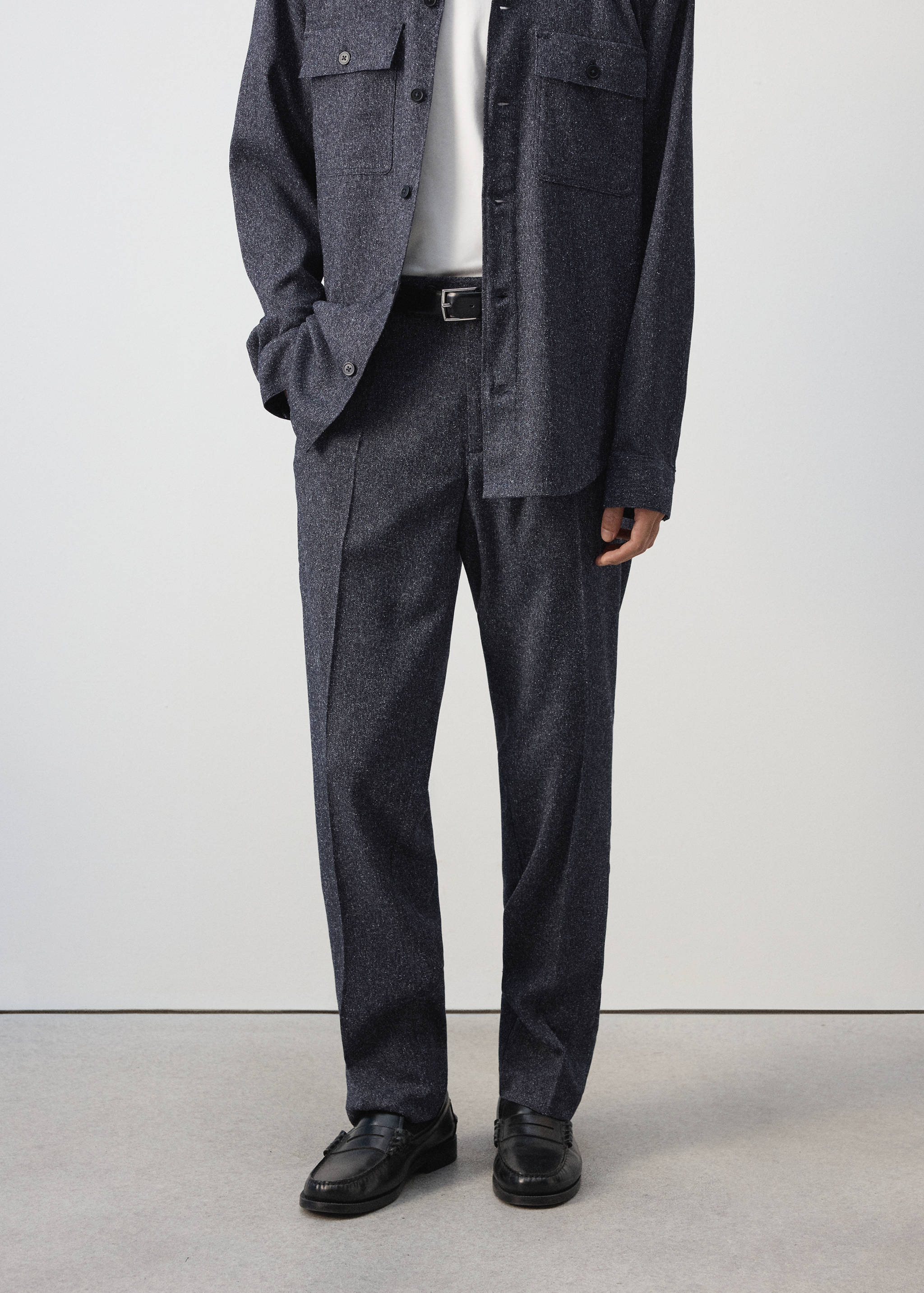 Dark grey melange straight trousers with pressed creases and a black leather belt.