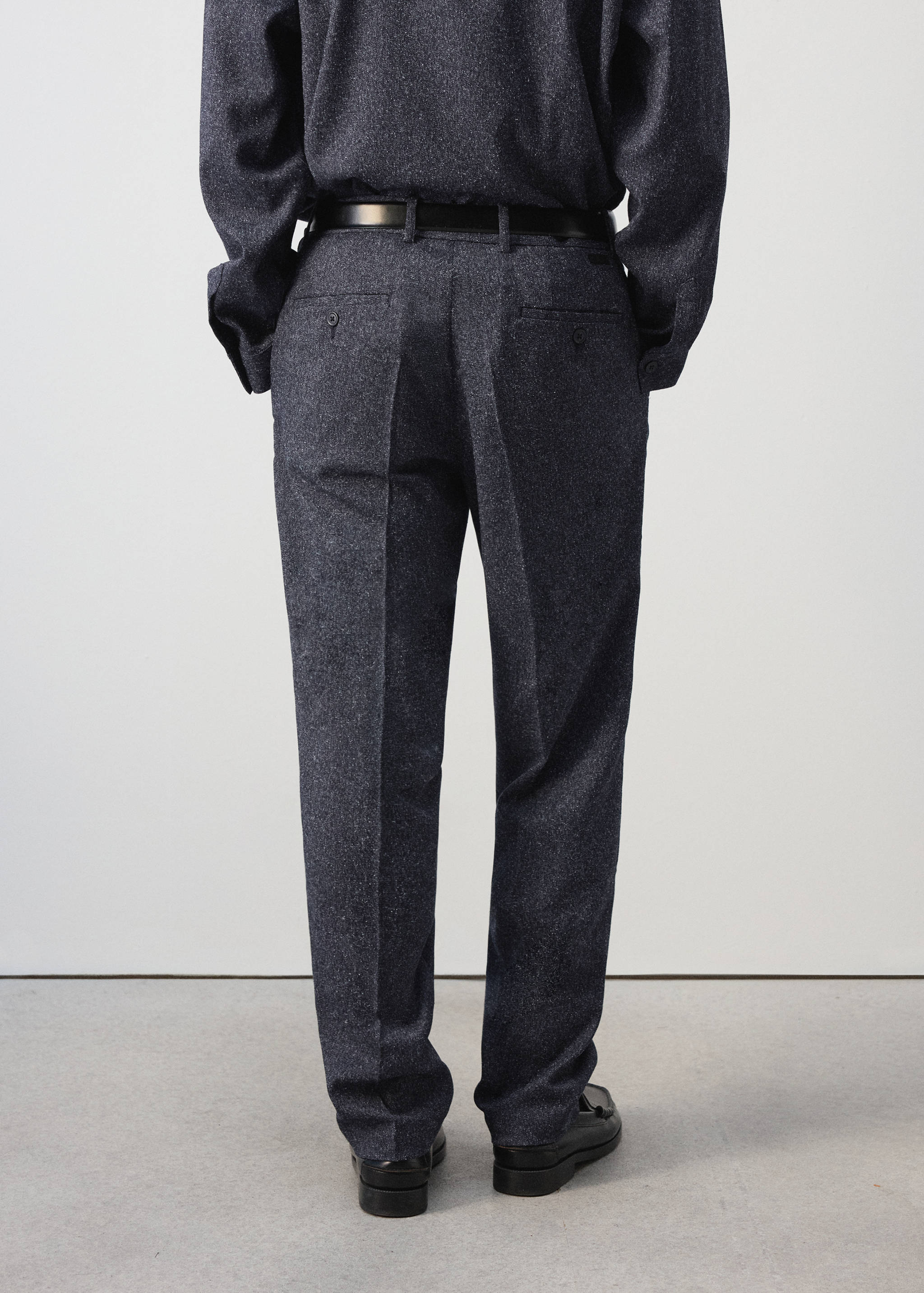 Dark grey melange trousers shown from the back, featuring a belt and back pockets.