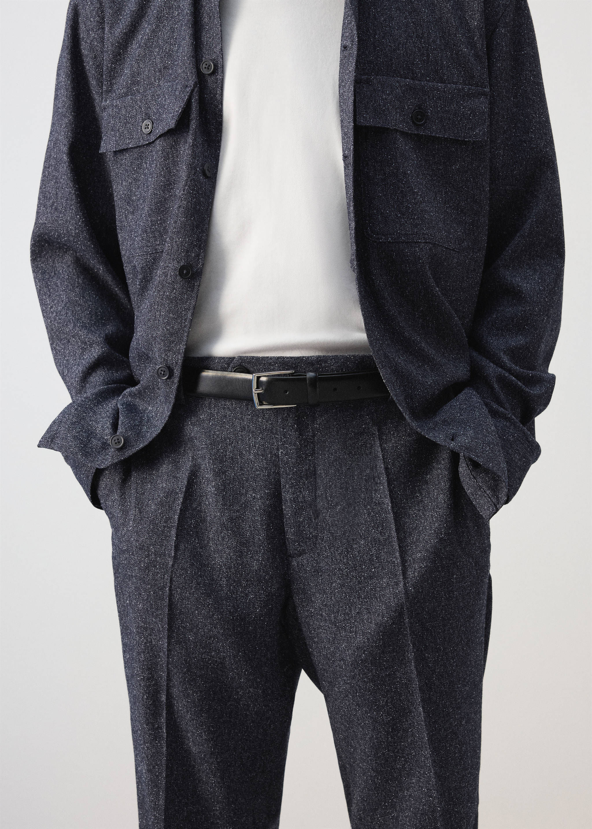 Dark grey pleated trousers worn with a black leather belt and matching overshirt.