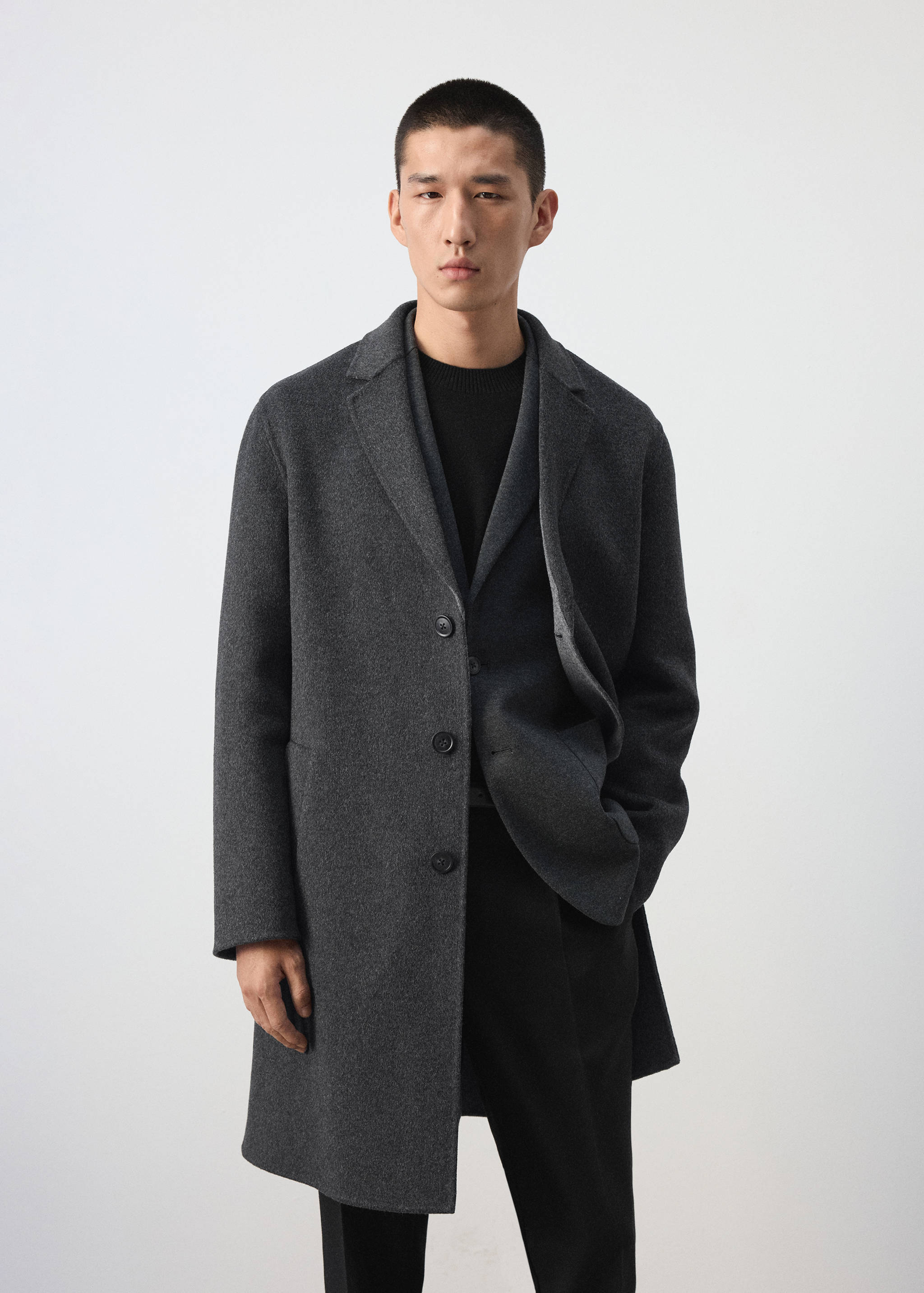 Dark charcoal grey single-breasted coat with notched lapel and front buttons.
