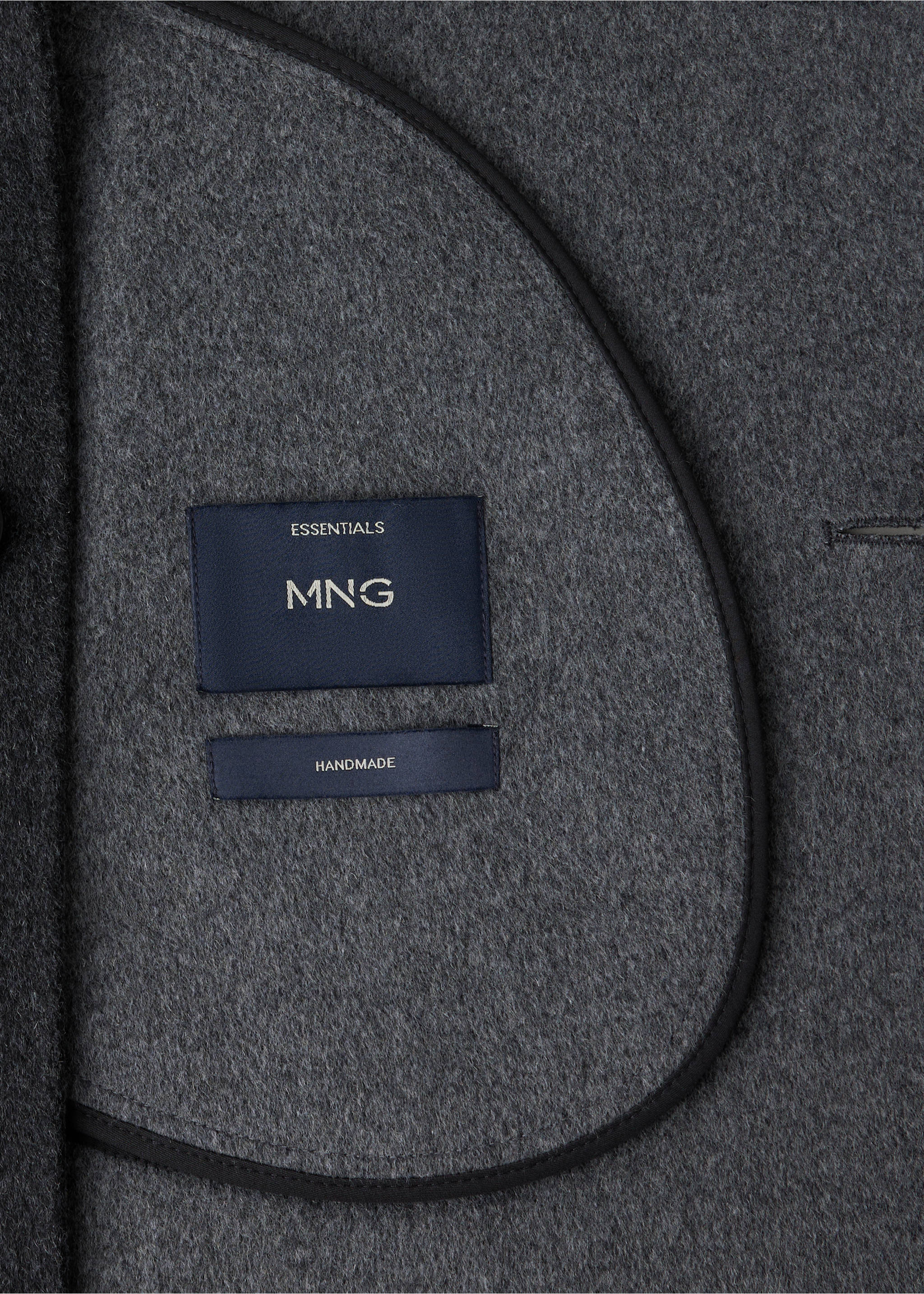 Close-up of the dark grey fabric and interior label of a handmade coat., Charcoal. Ref: 37047886-00.