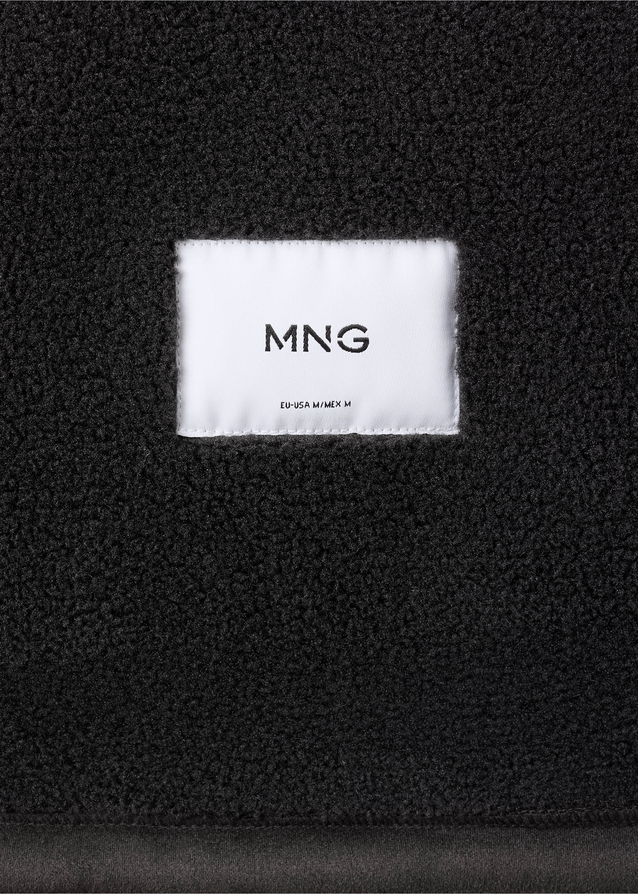 Close-up of black jacket faux-shearling fabric with brand label., Dark Green. Ref: 37047889-00.