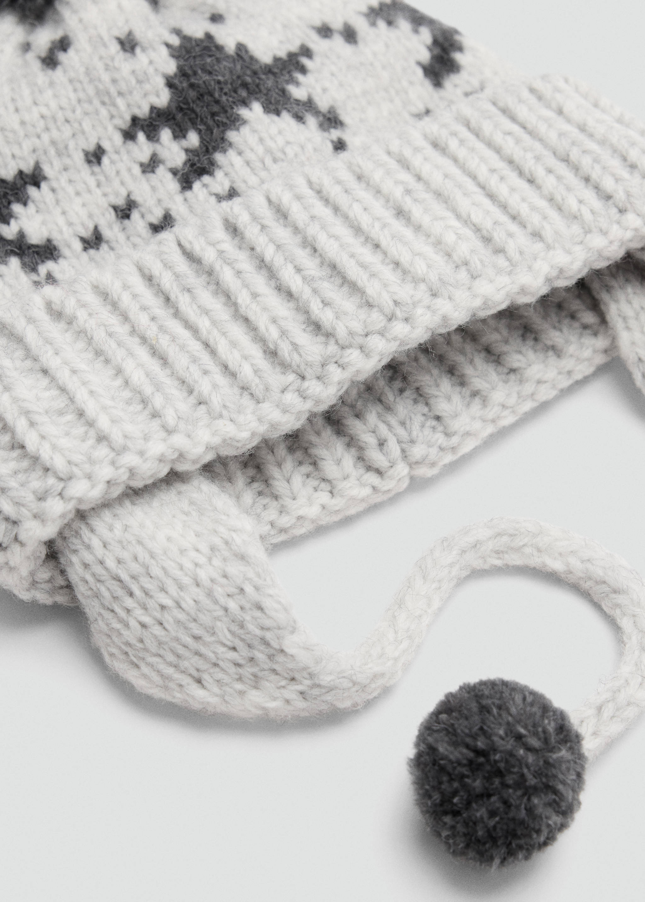 Grey and white knitted beanie with earflaps and pom-pom ties.