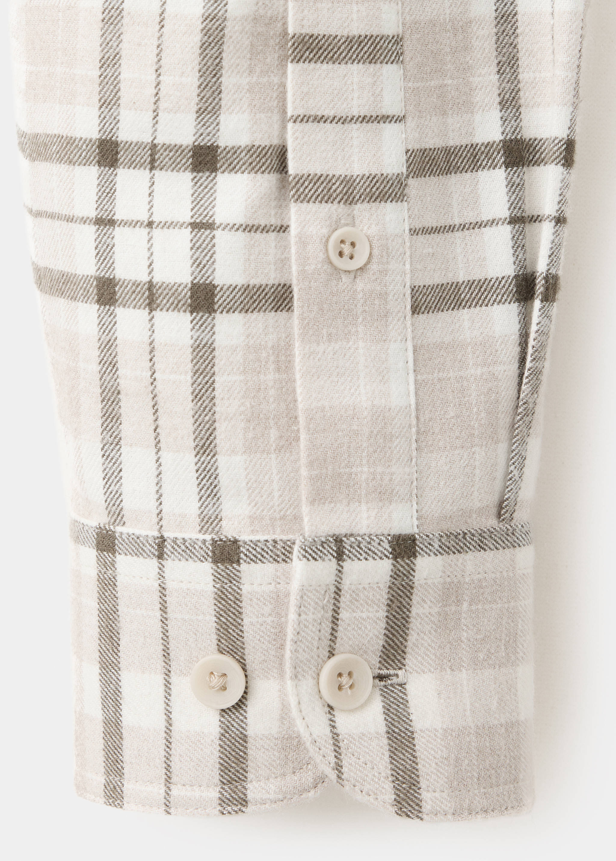 Close-up of a beige and white checked overshirt fabric and cuff.