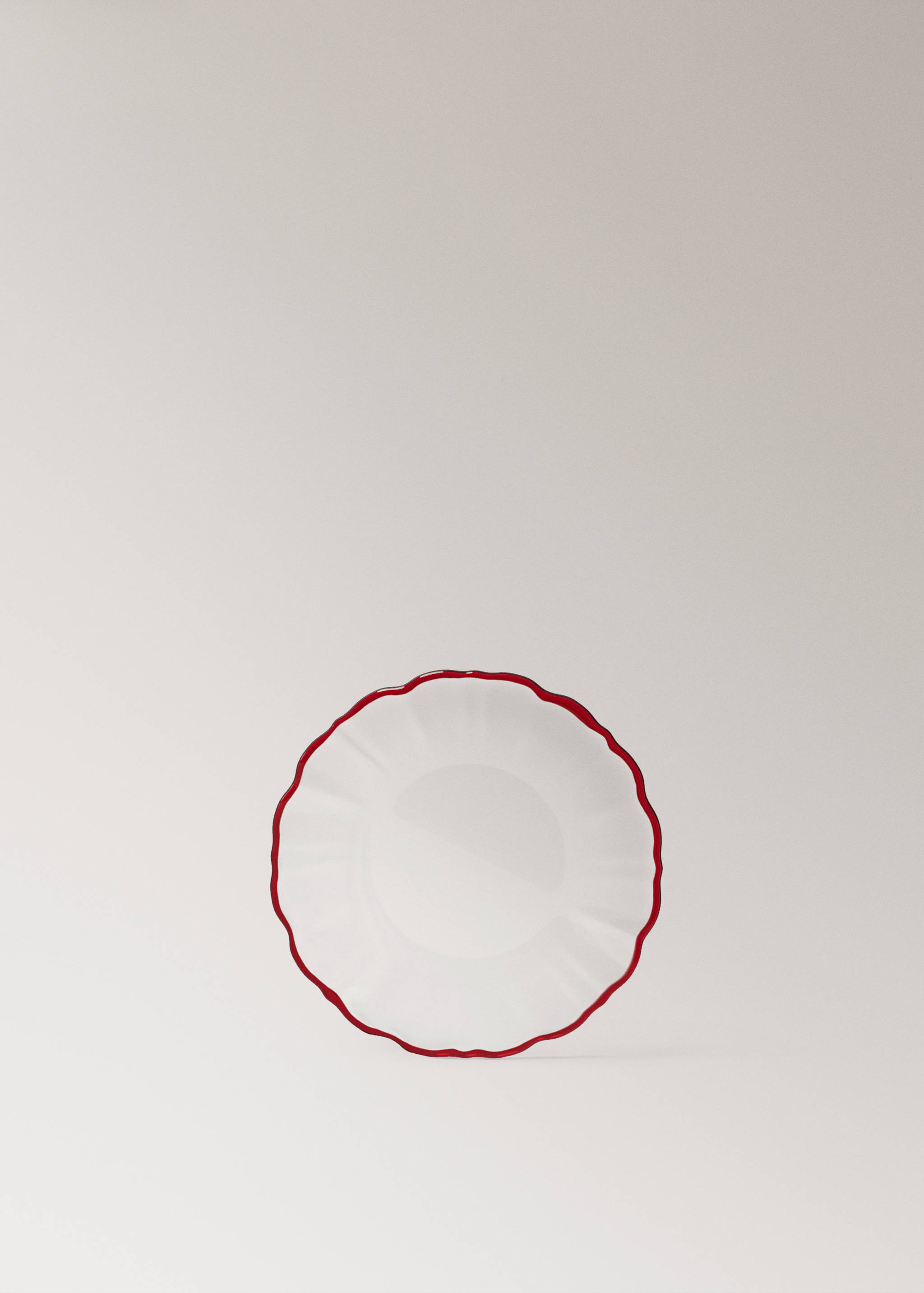 Round glass plate with a wavy rim and a red border.