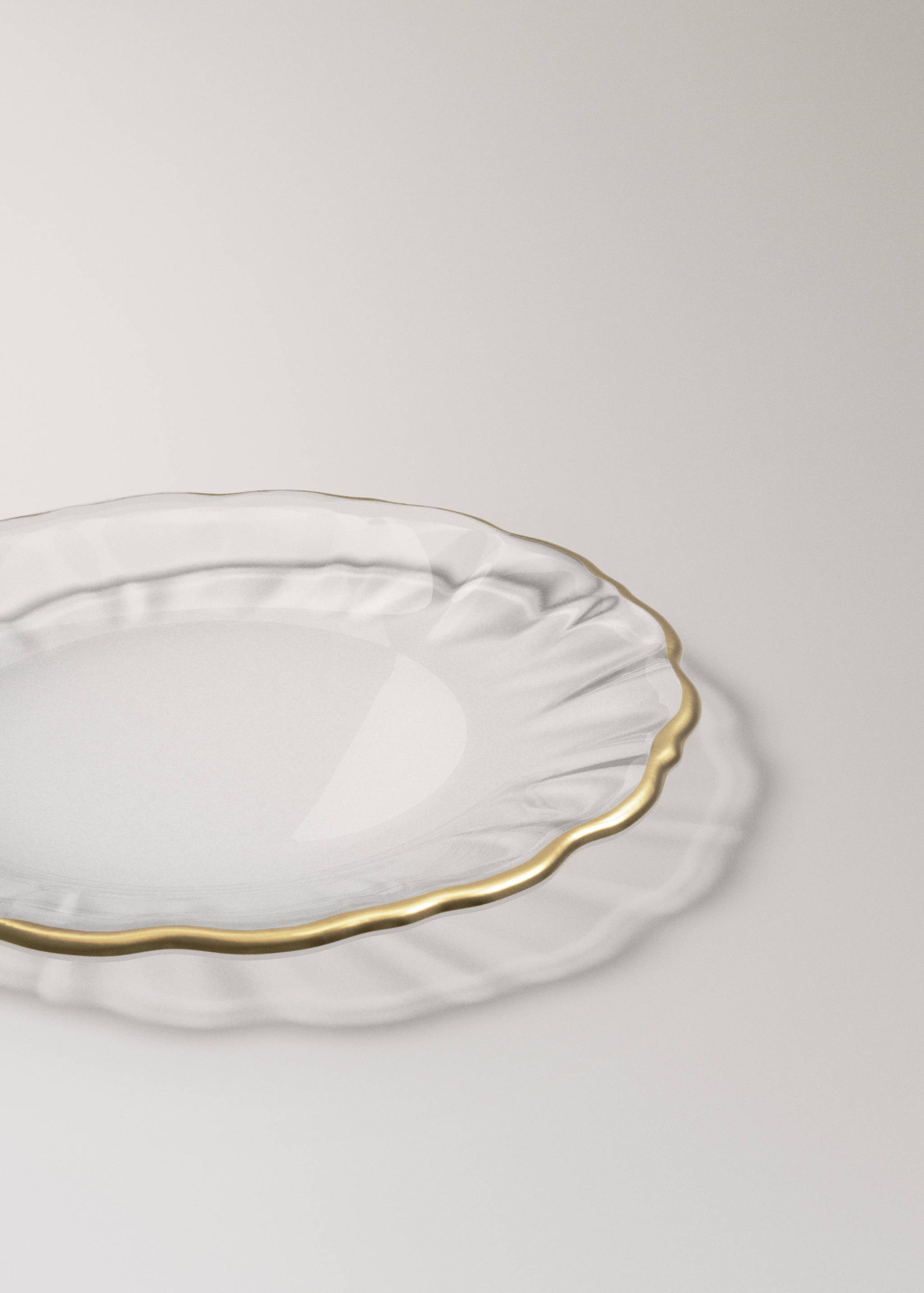 Clear glass plate with a wavy rim and a gold-colored edge.