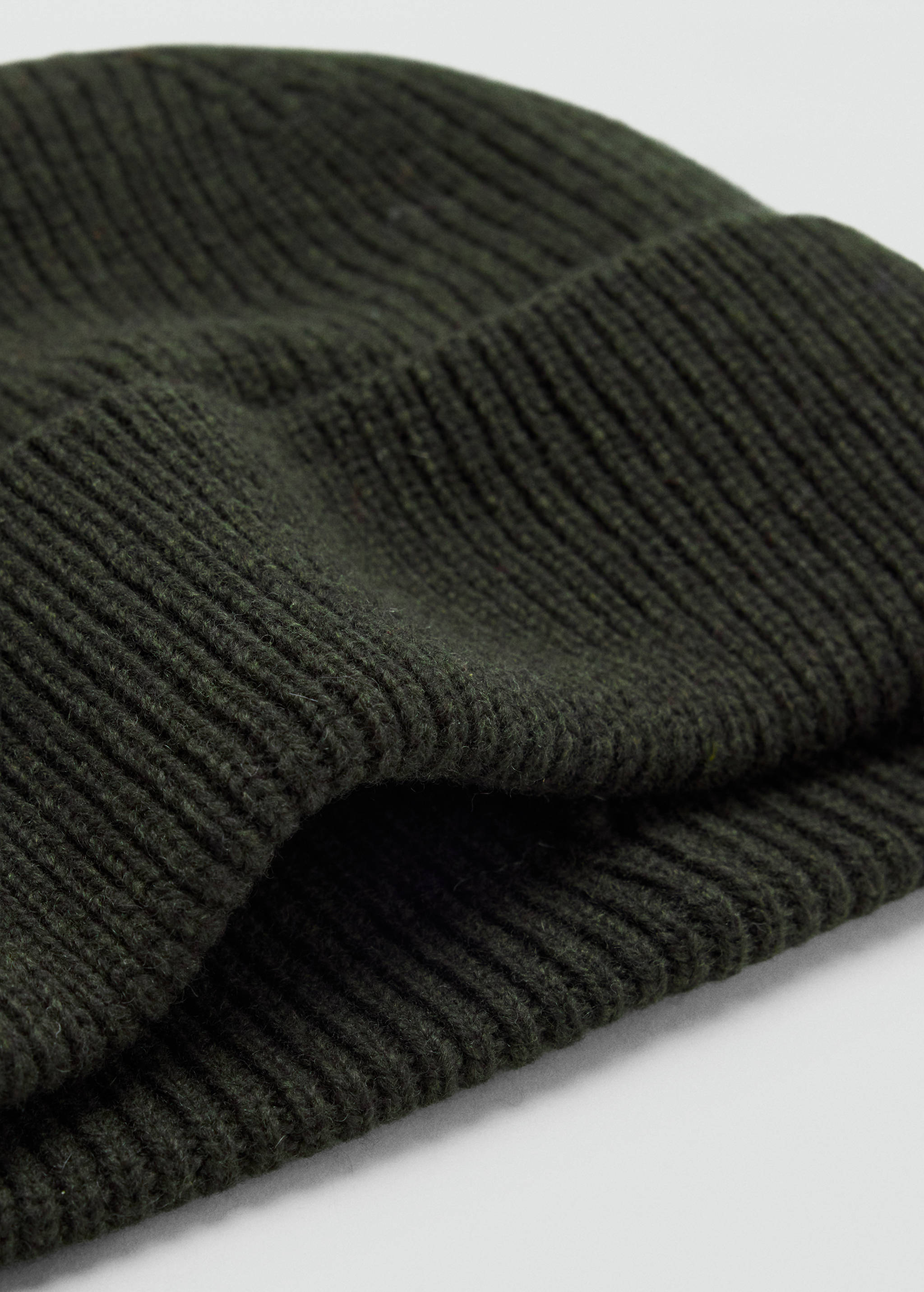 Dark green ribbed knit beanie in a close-up view.