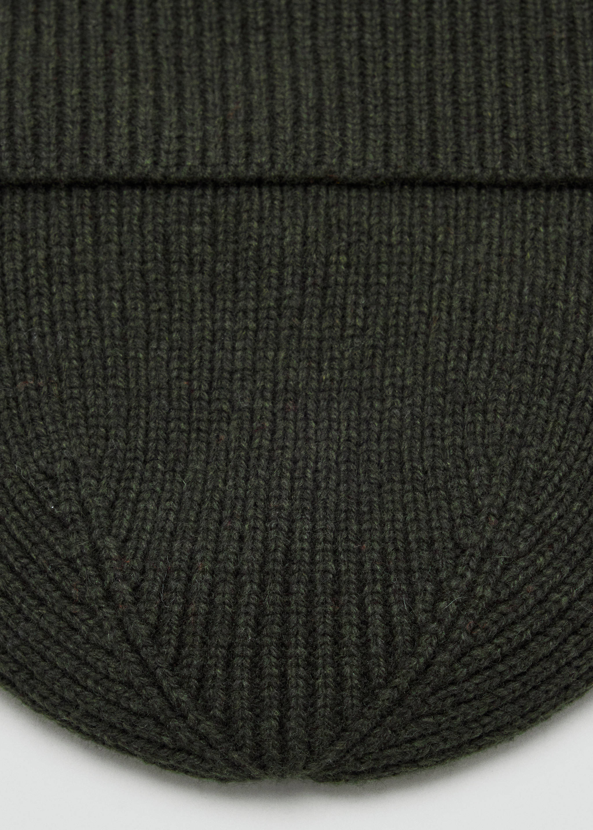 Dark green ribbed knit beanie in a close-up view.