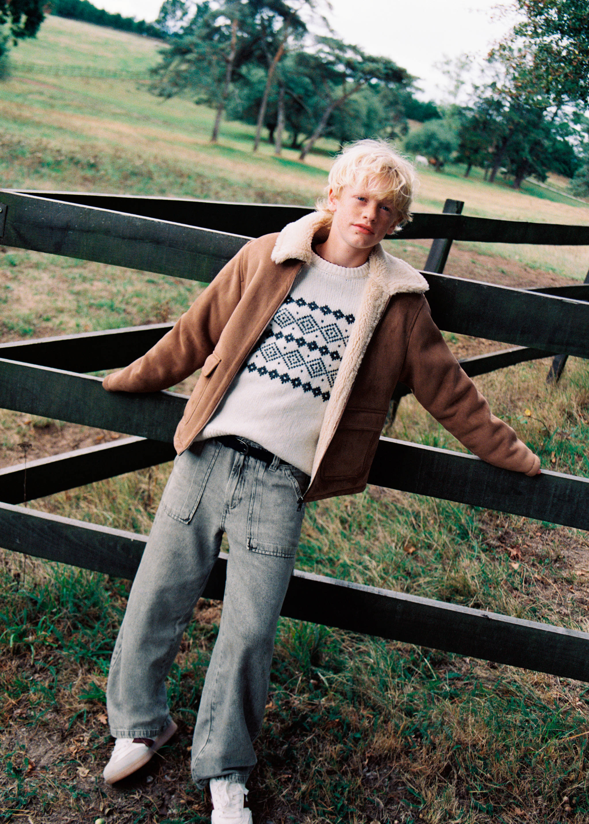 Grey denim trousers worn by a child with a patterned jumper and brown faux-shearling jacket.