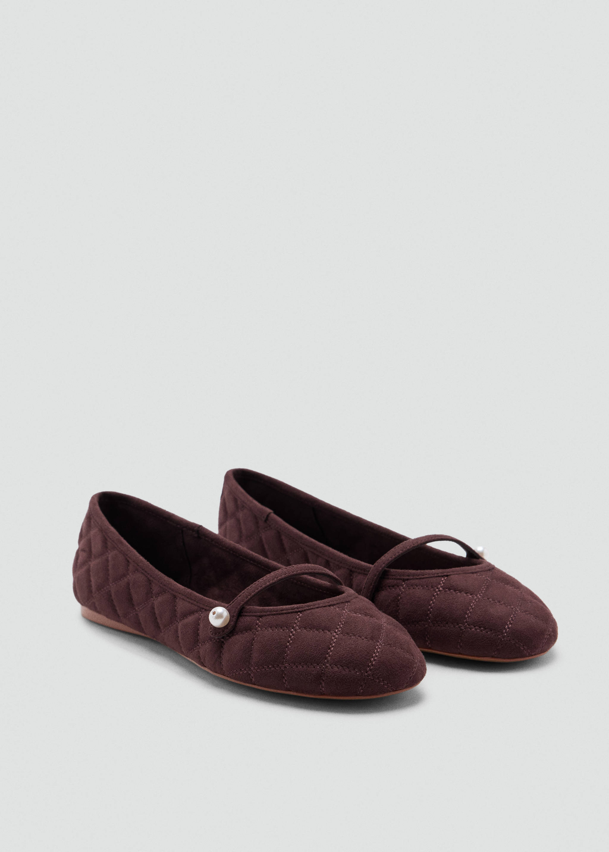 Dark brown quilted flats with a thin instep strap and pearl detail.