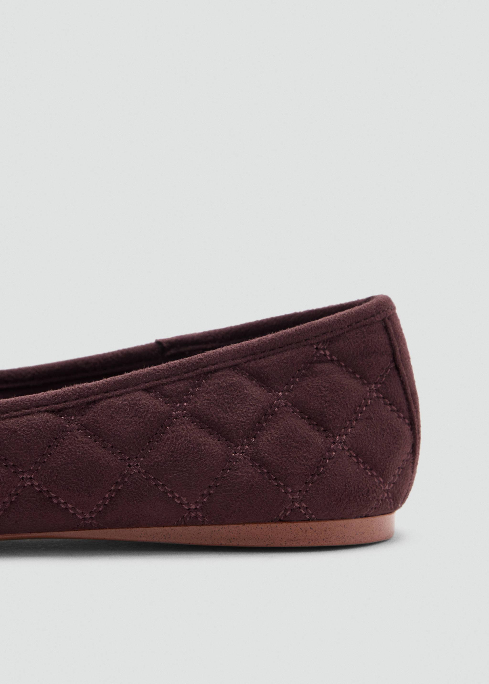 Burgundy quilted flat shoe heel detail.