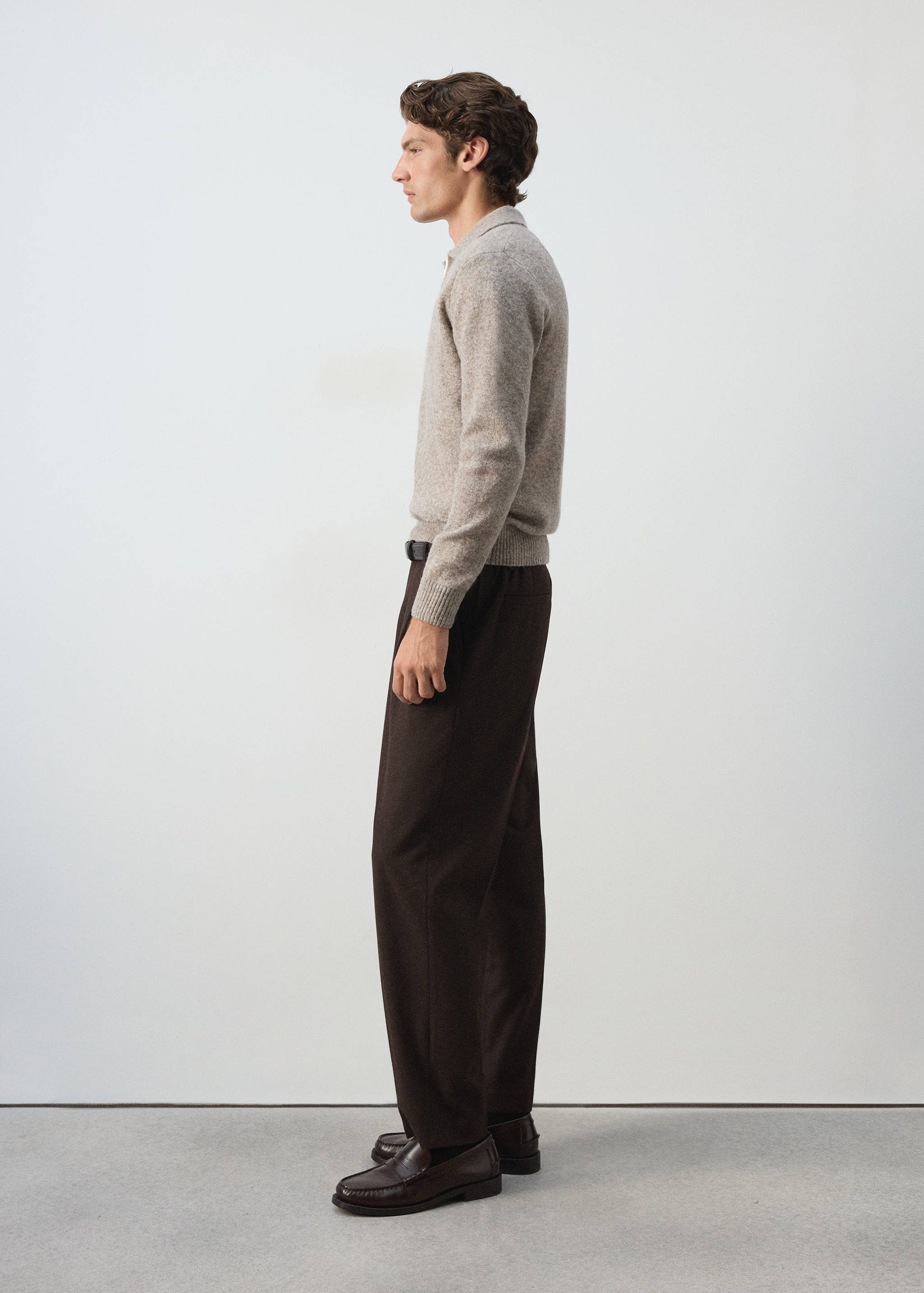 Beige knitted polo shirt with long sleeves and a collar.
