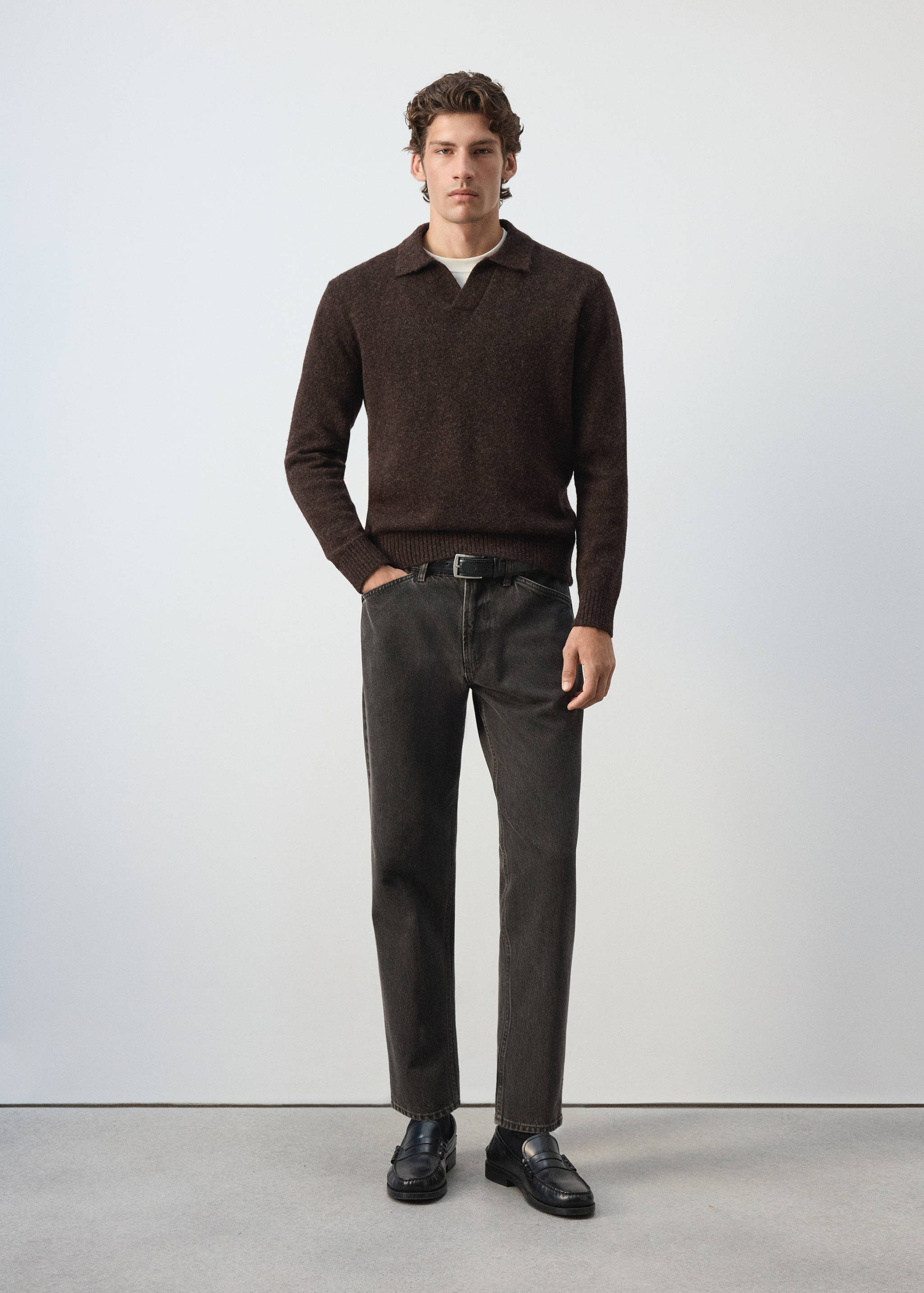 Brown knitted polo shirt with long sleeves and a V-neck collar, worn with dark trousers.