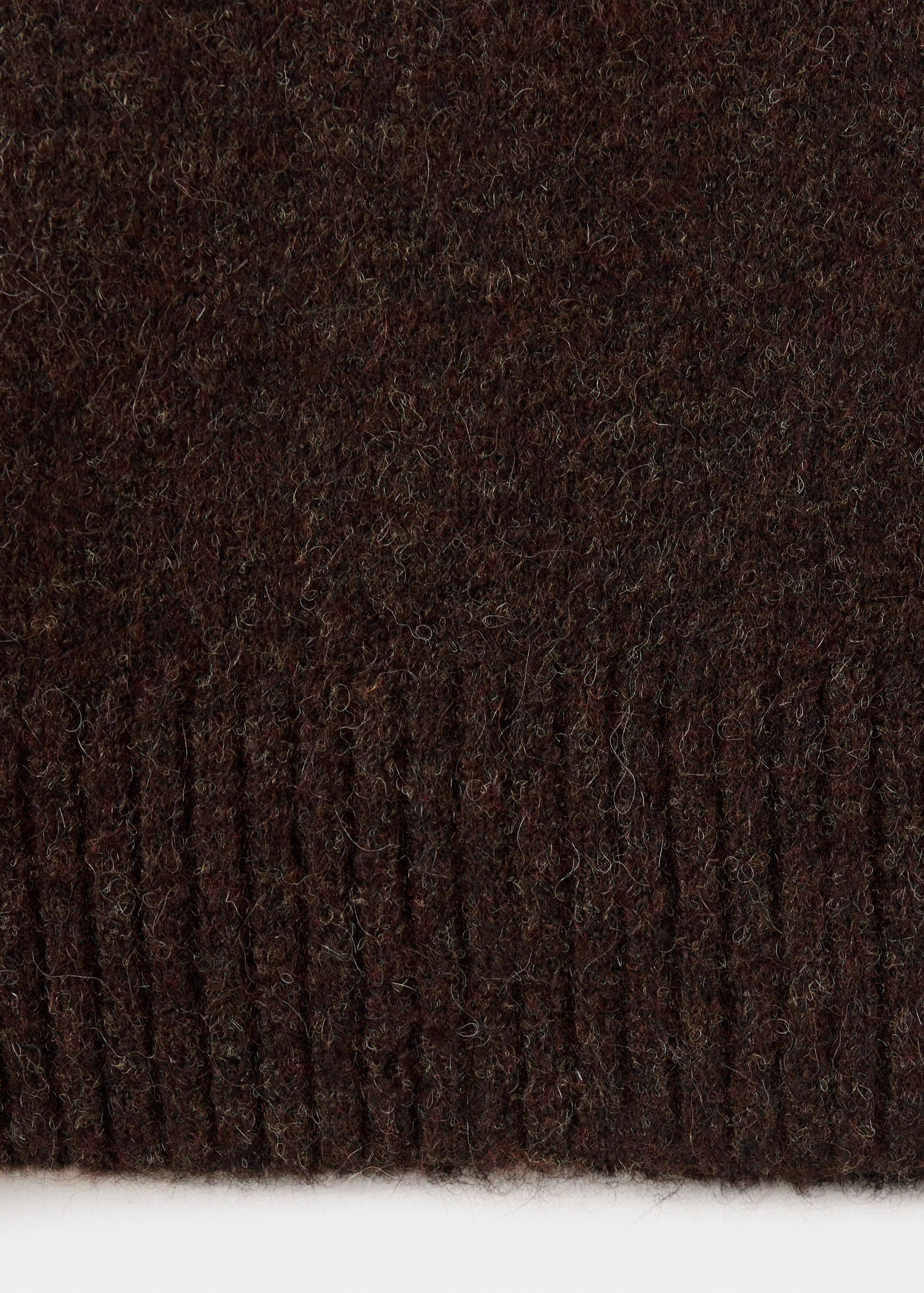 Close-up of the textured brown knit fabric and ribbed hem of a polo.