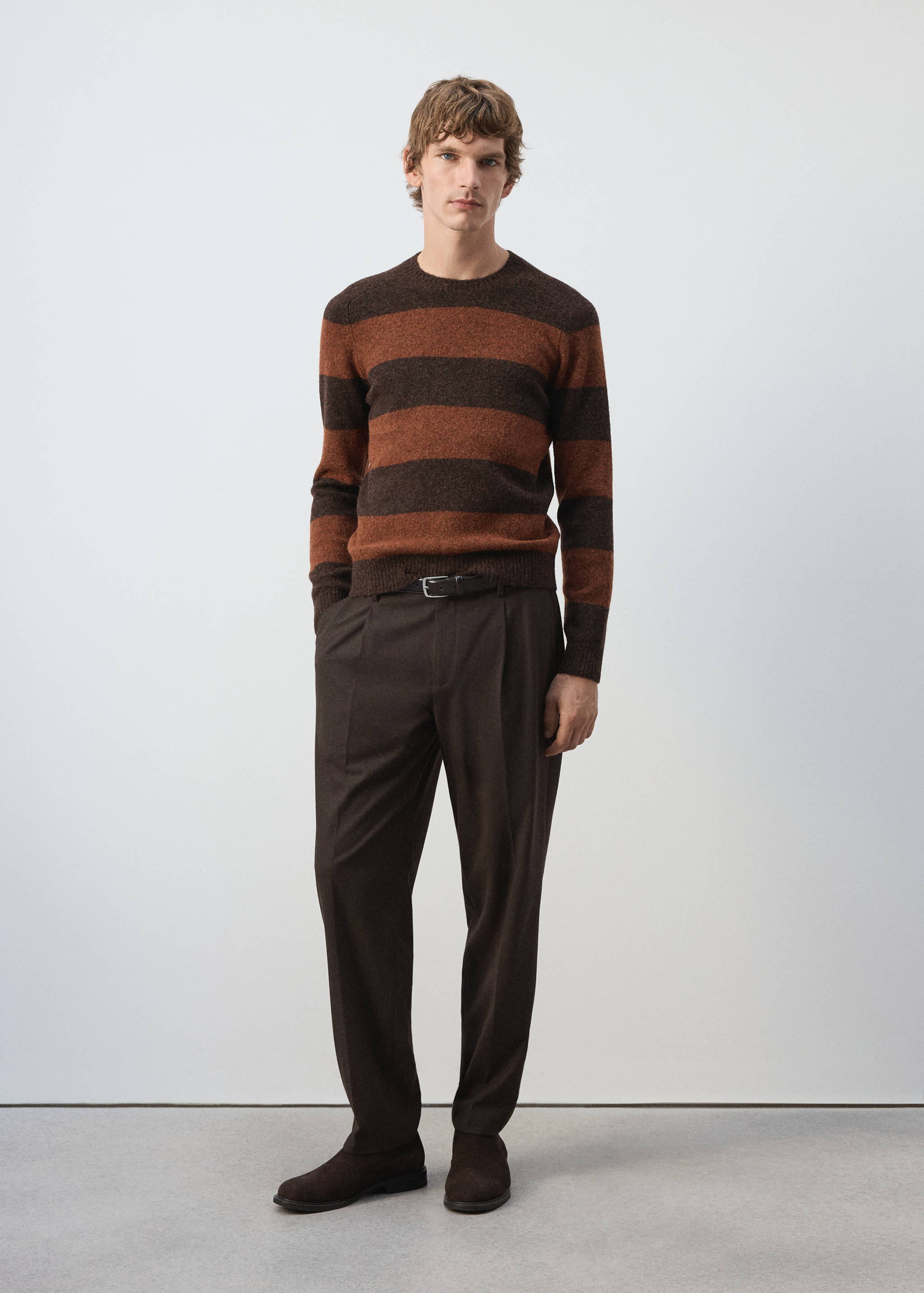 Brown and rust orange striped crew neck jersey worn with brown trousers.