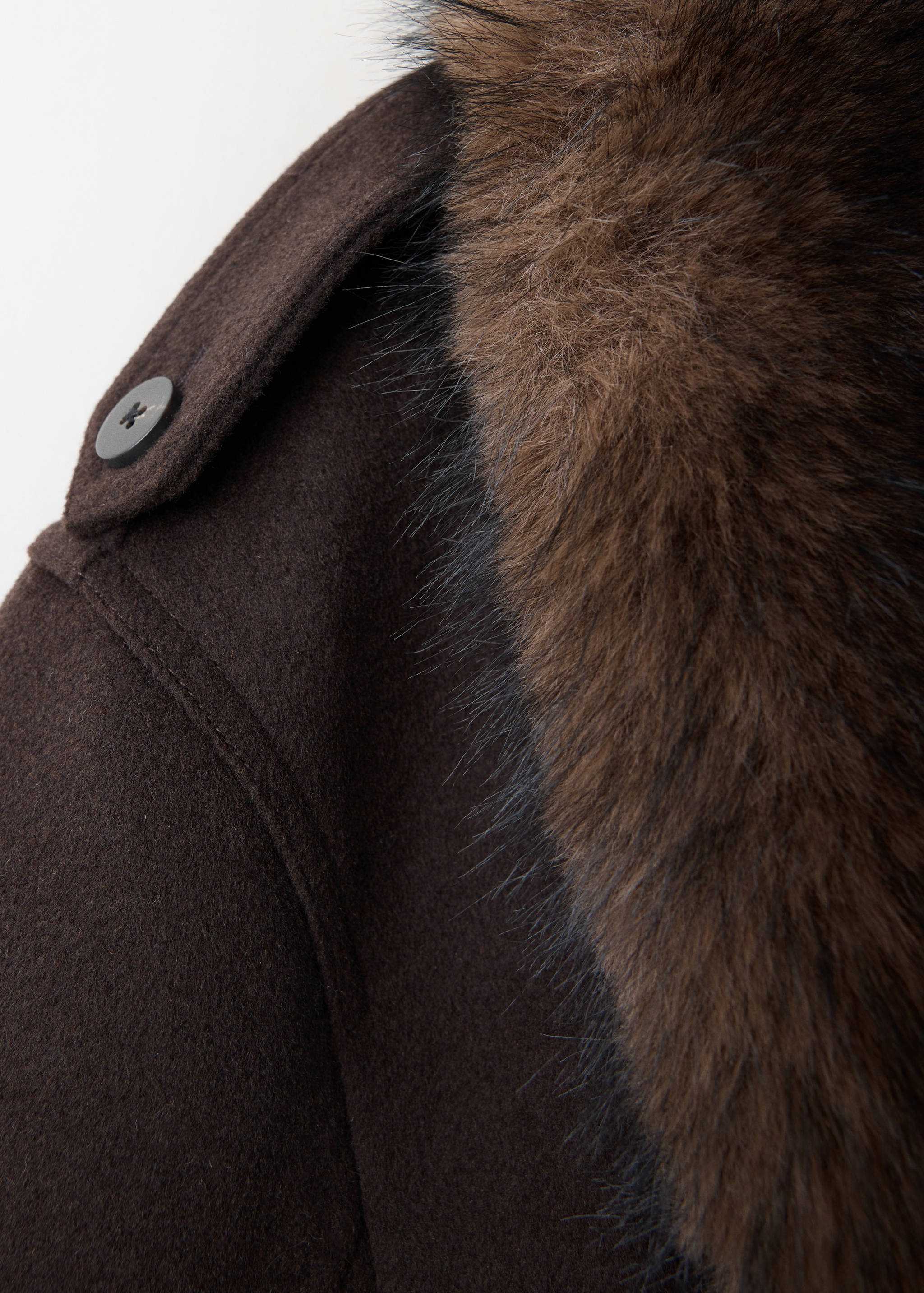 Close-up of a brown jacket with a plush faux-fur collar and buttoned epaulette.