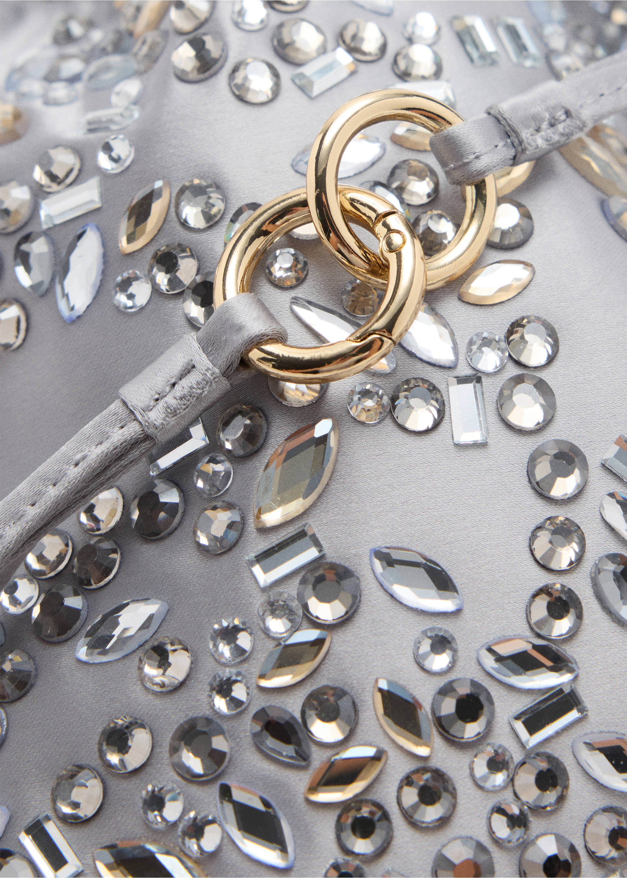 Close-up of a silver rhinestone-embellished handbag with gold rings., Light/Pastel Grey. Ref: 37047924-00.