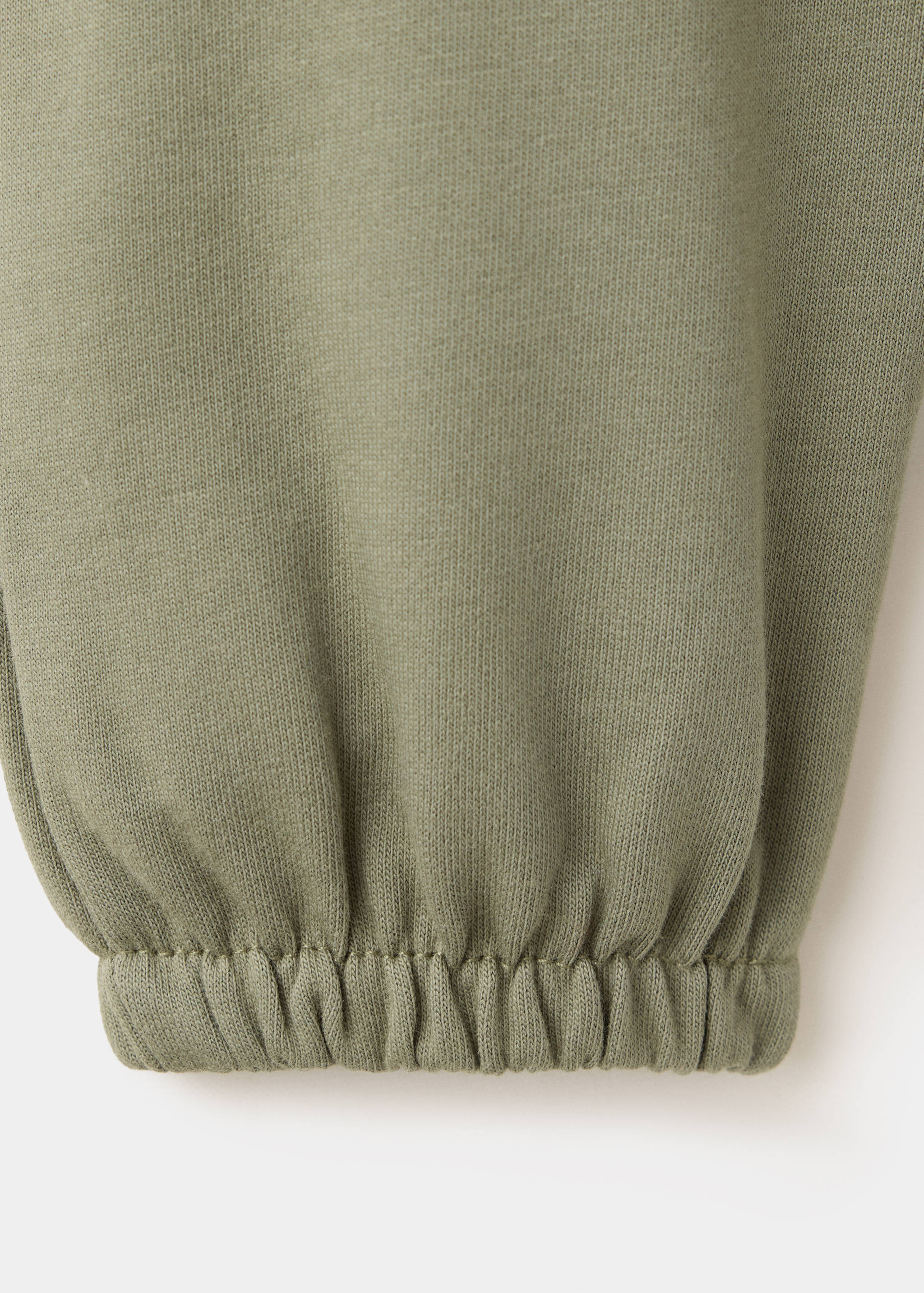 Close-up of the fabric and elasticated cuff of khaki green joggers.