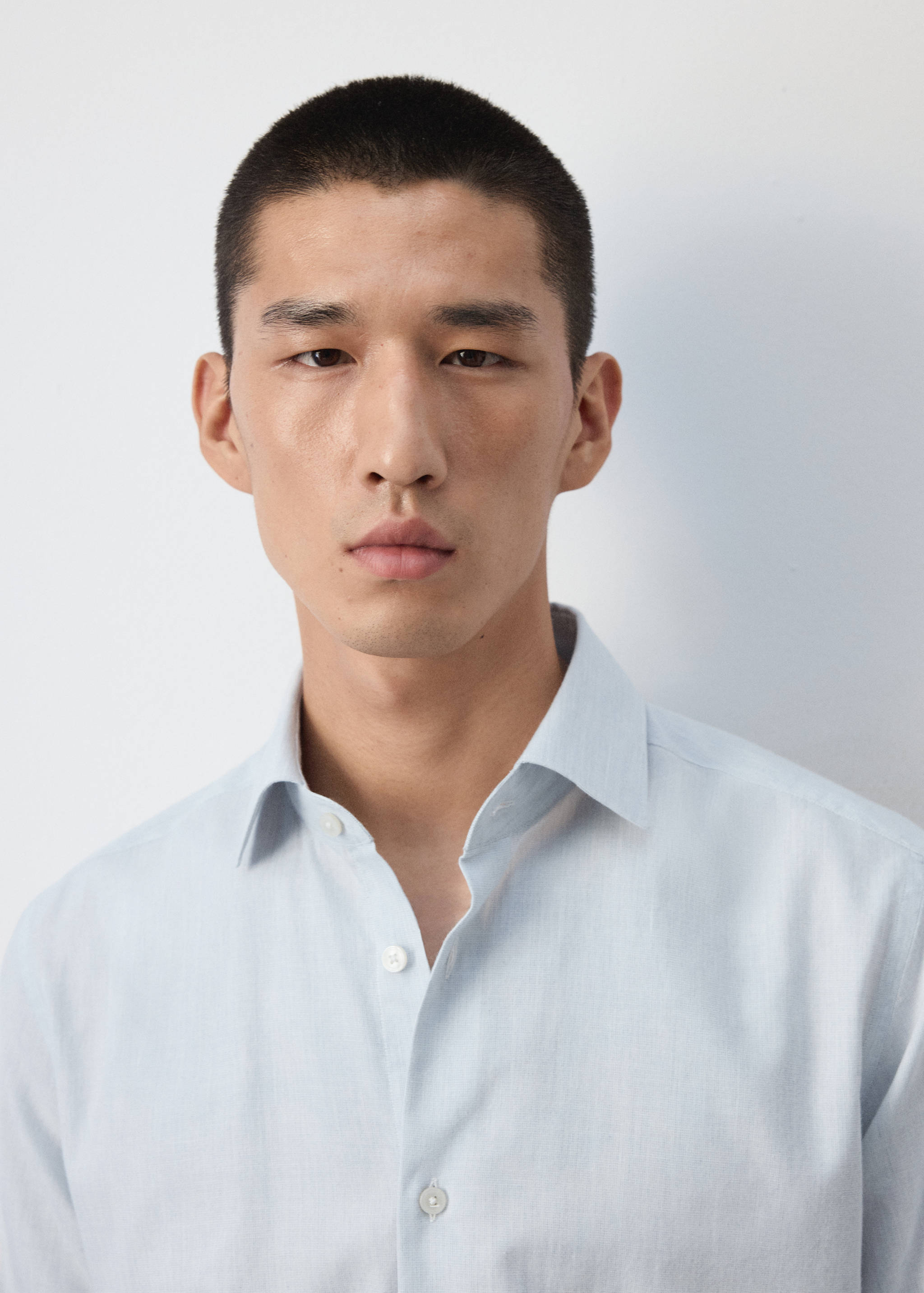 Close-up portrait of a man wearing a light blue shirt with a classic collar.