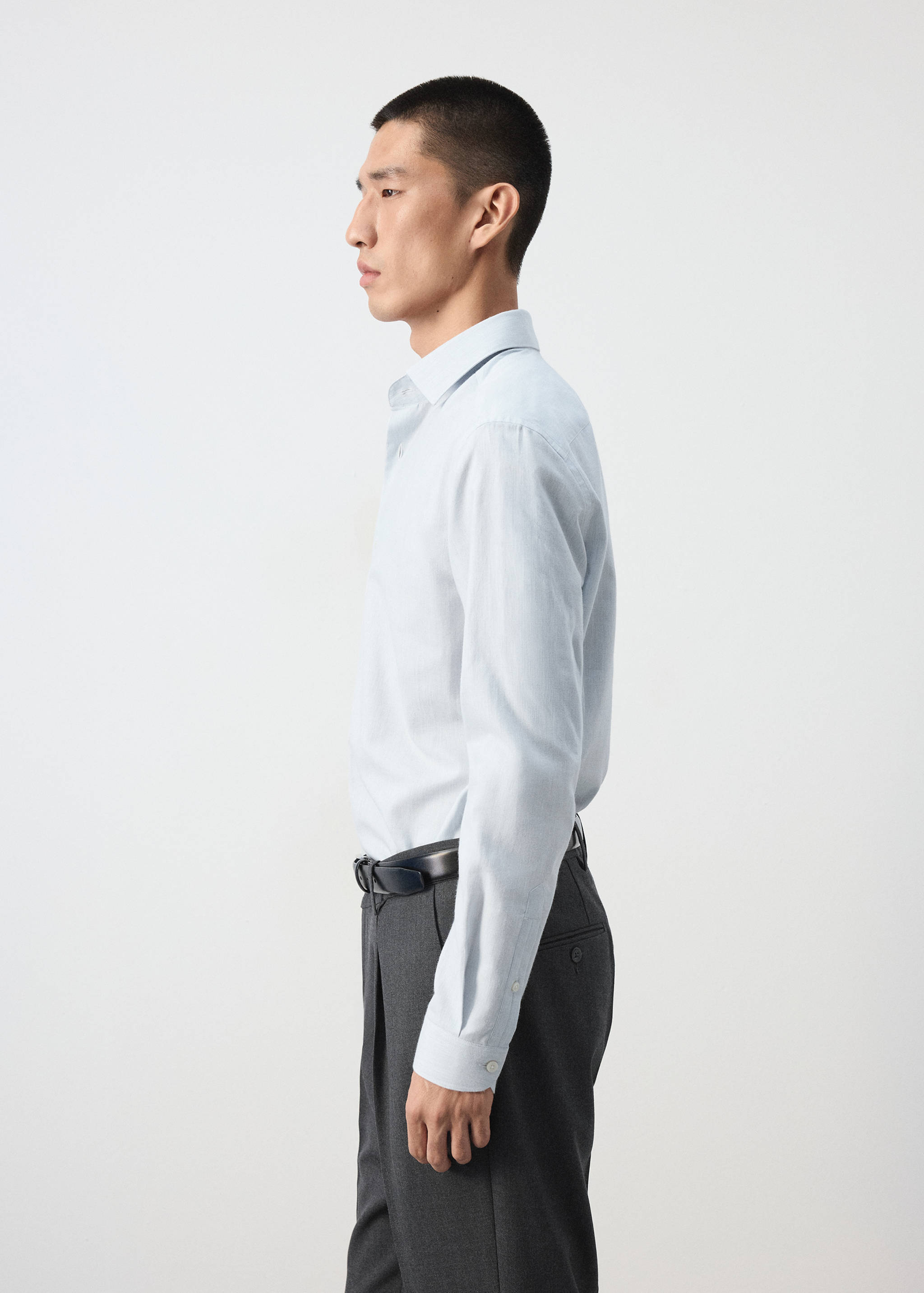 Light blue long-sleeve shirt with a classic collar, worn tucked in.