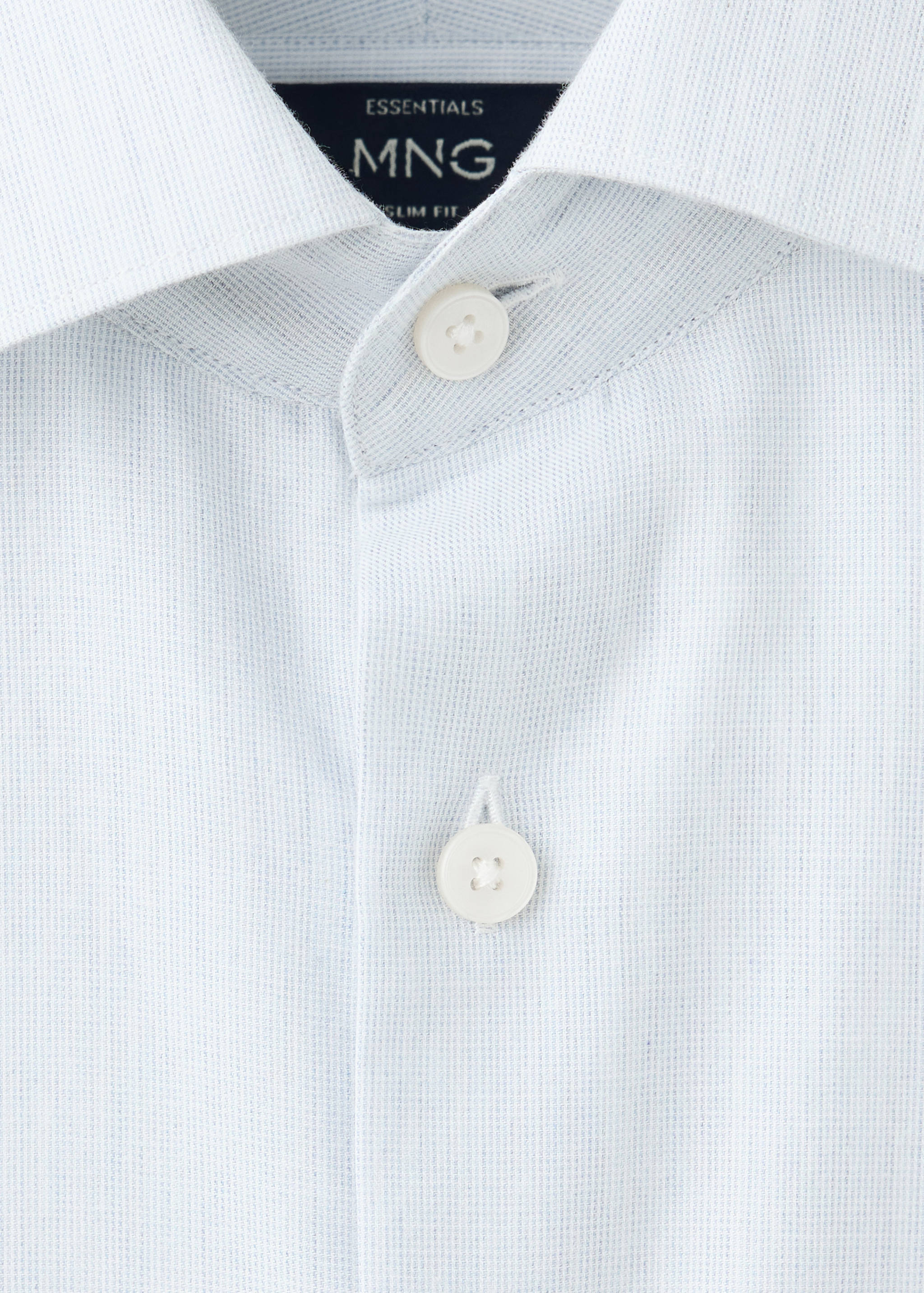 Close-up of a light blue patterned shirt collar and button placket.