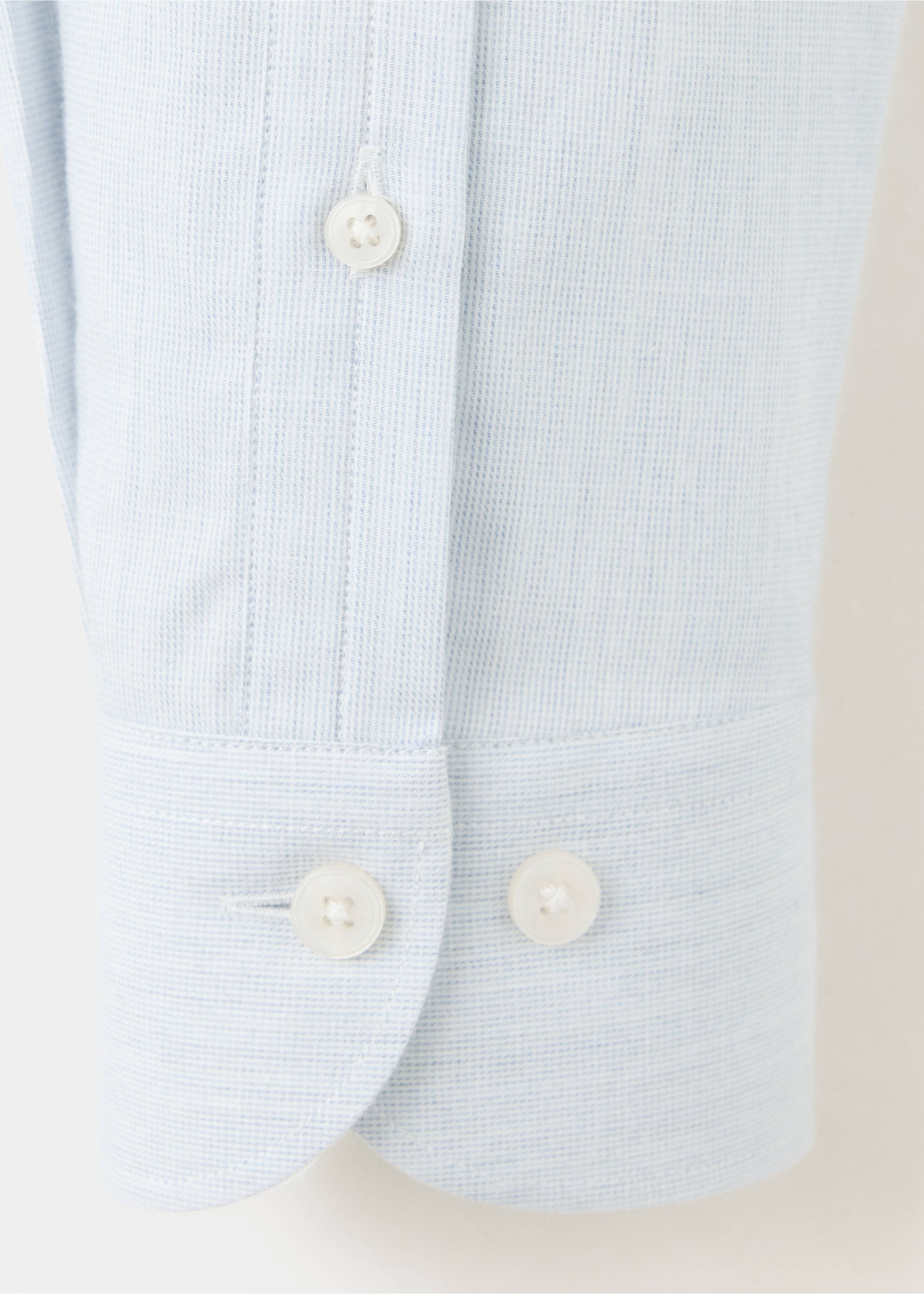 Close-up of a light blue textured shirt cuff and placket with white buttons., White. Ref: 37047934-00.
