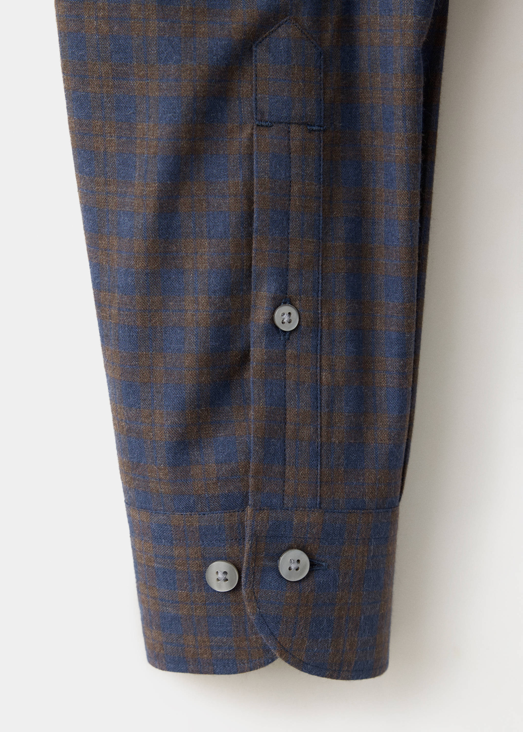 Close-up of a blue and brown checked shirt cuff and placket.