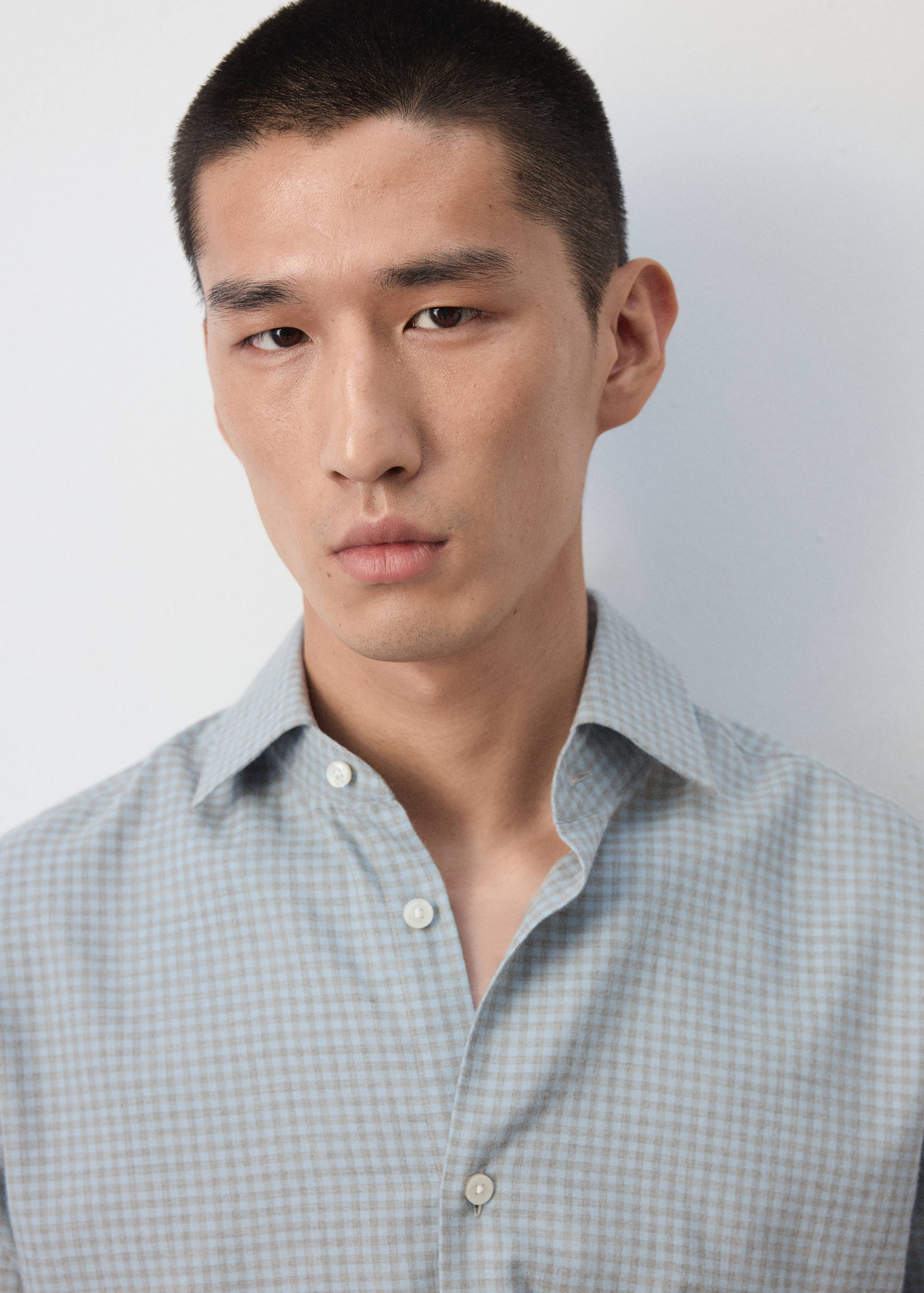 Close-up of a light blue and grey checked shirt with a classic collar.
