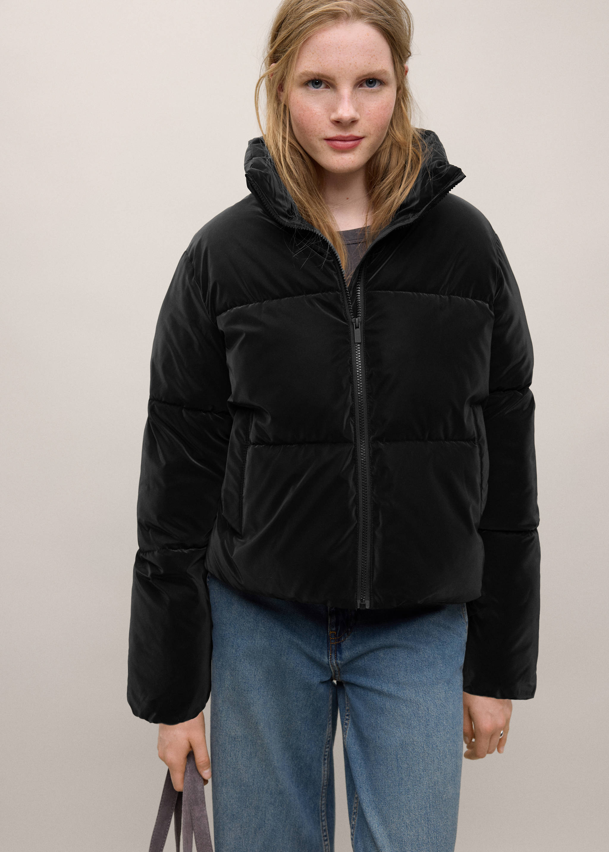 Anorak acolchado negro con cuello alto y cremallera delantera.