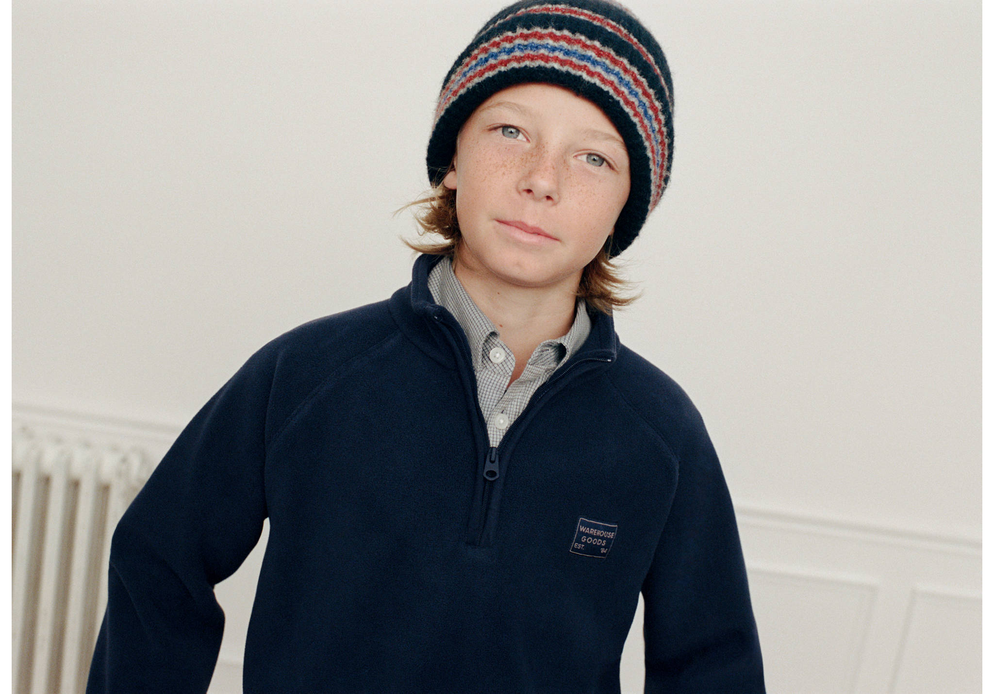 Striped beanie in dark blue with red and blue bands, worn by a boy.