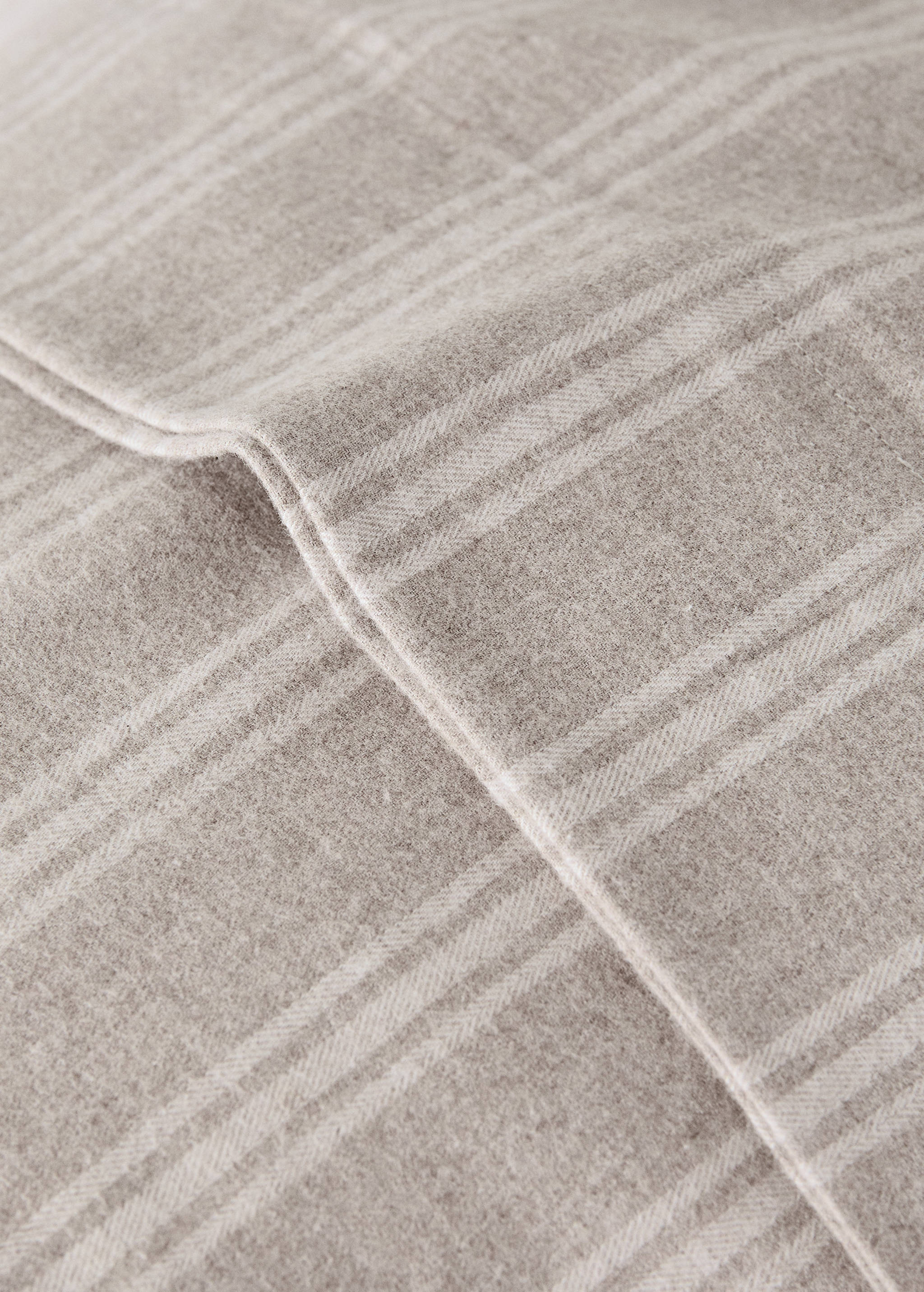 Beige checked pillowcase detail with textured fabric.