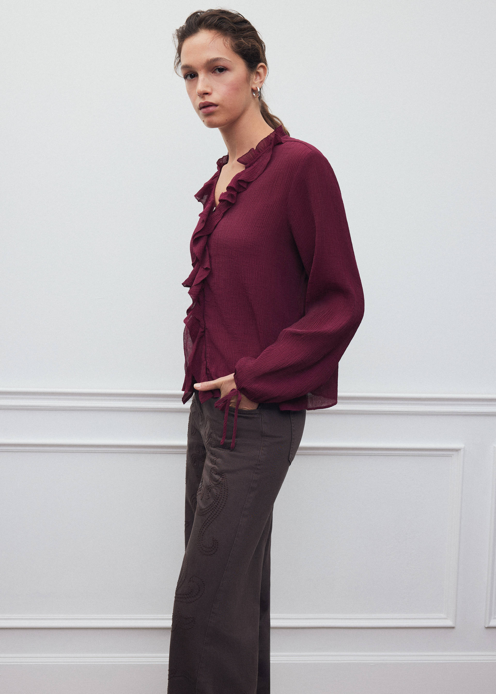 Burgundy ruffle-trim V-neck shirt with long sleeves.
