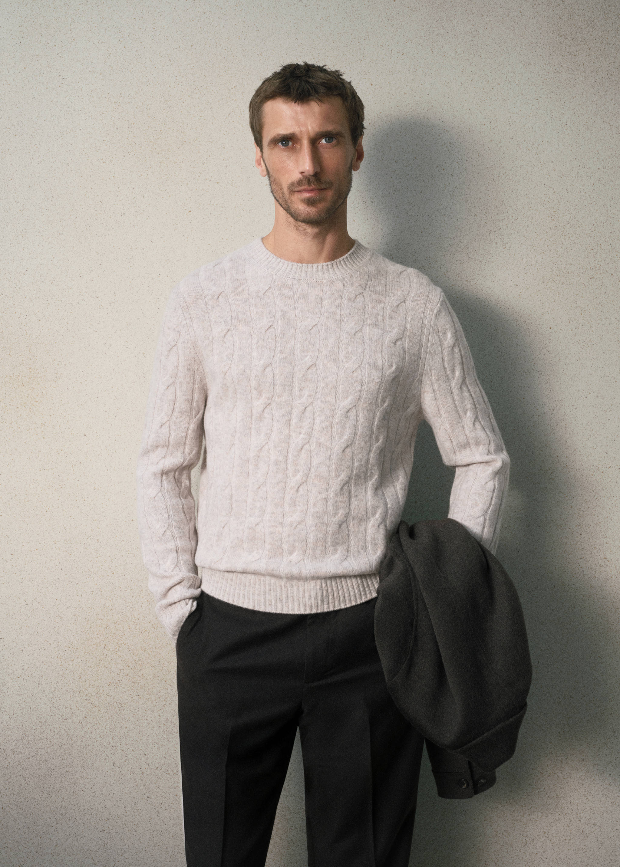 Beige cable-knit jumper with a round ribbed neck.
