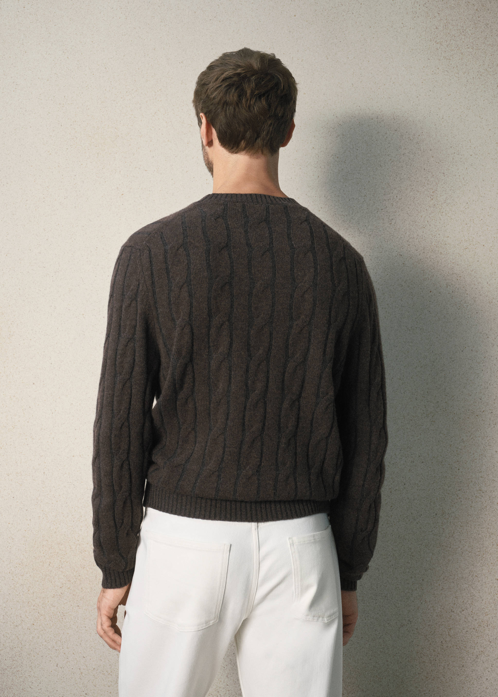 Back view of a dark brown cable-knit jumper with a crew neck.