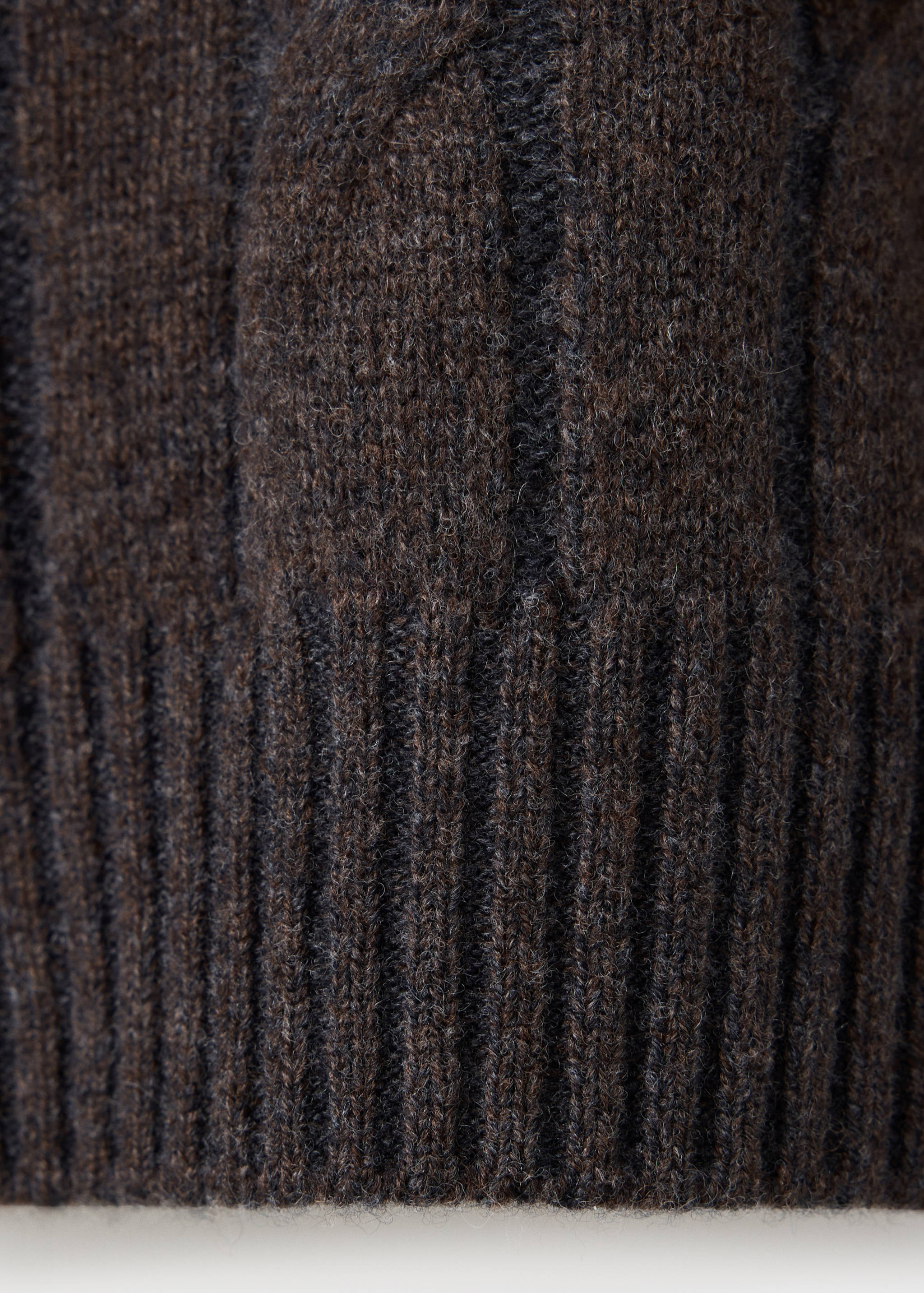 Close-up of a dark brown men's knit sweater showing texture and ribbed hem.