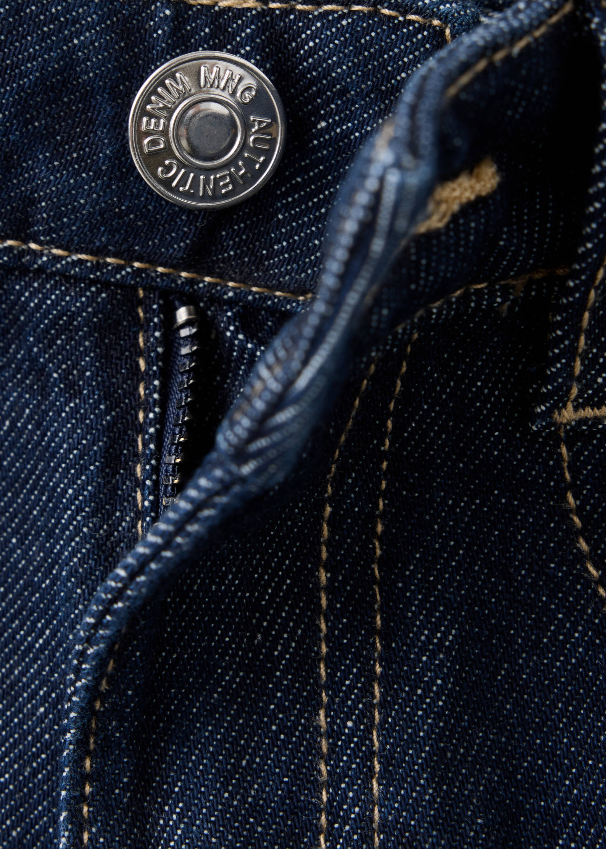 Primer plano de unos vaqueros de tejido vaquero azul oscuro con botón metálico y costuras en contraste., Azul. Ref: 37048277-00.