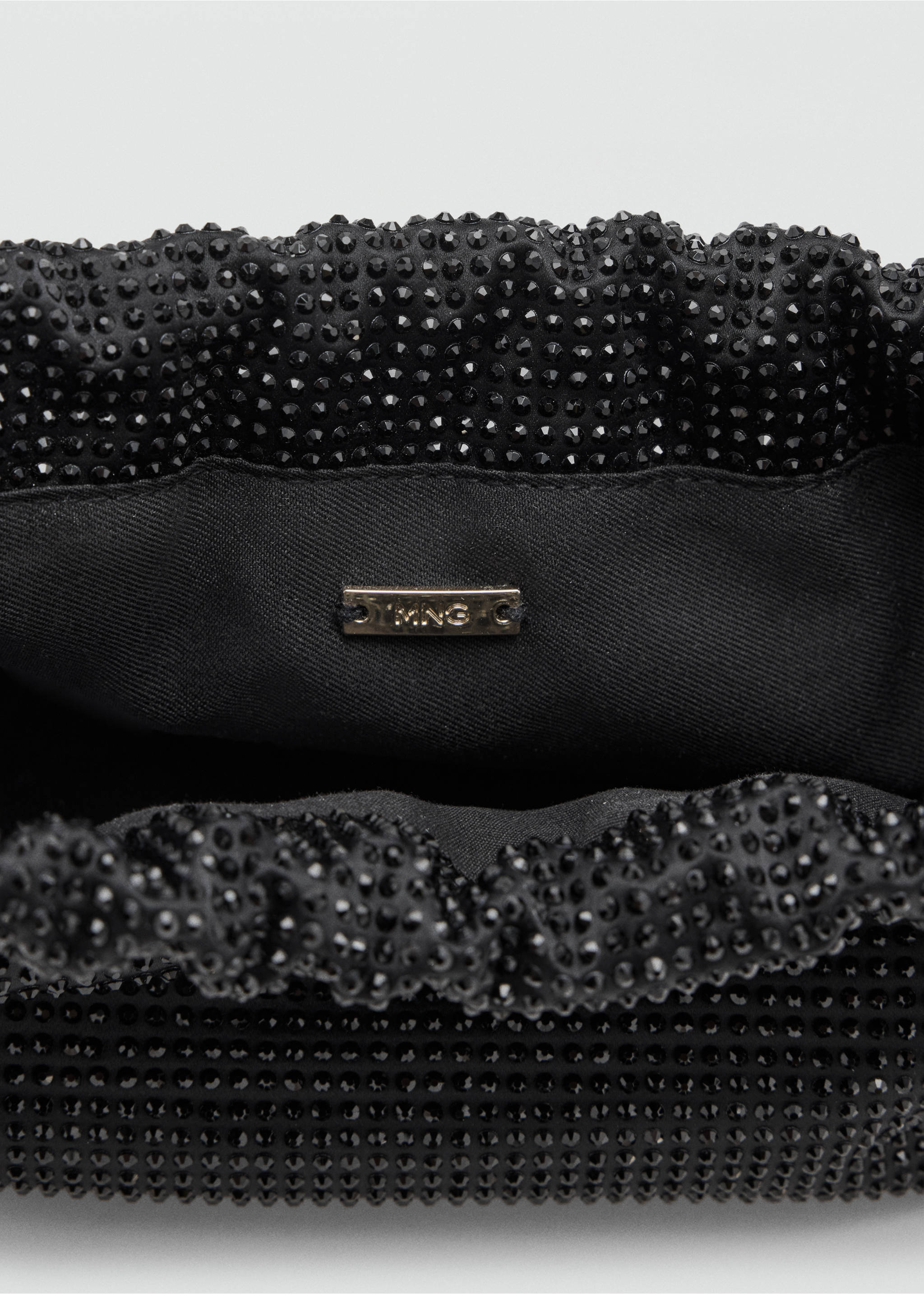 Close-up of a black rhinestone shoulder bag interior detail., Black. Ref: 37048279-00.