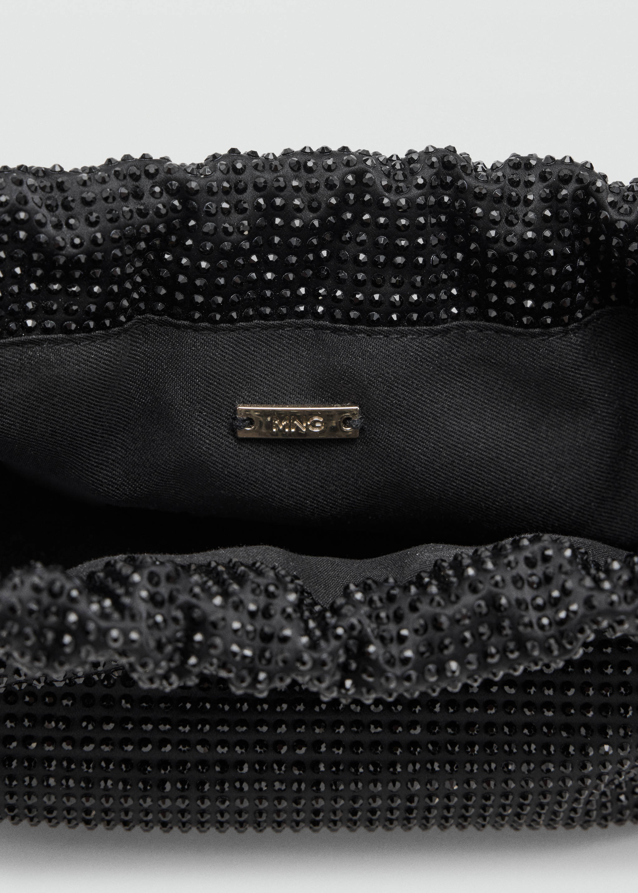 Close-up of a black rhinestone shoulder bag interior detail.