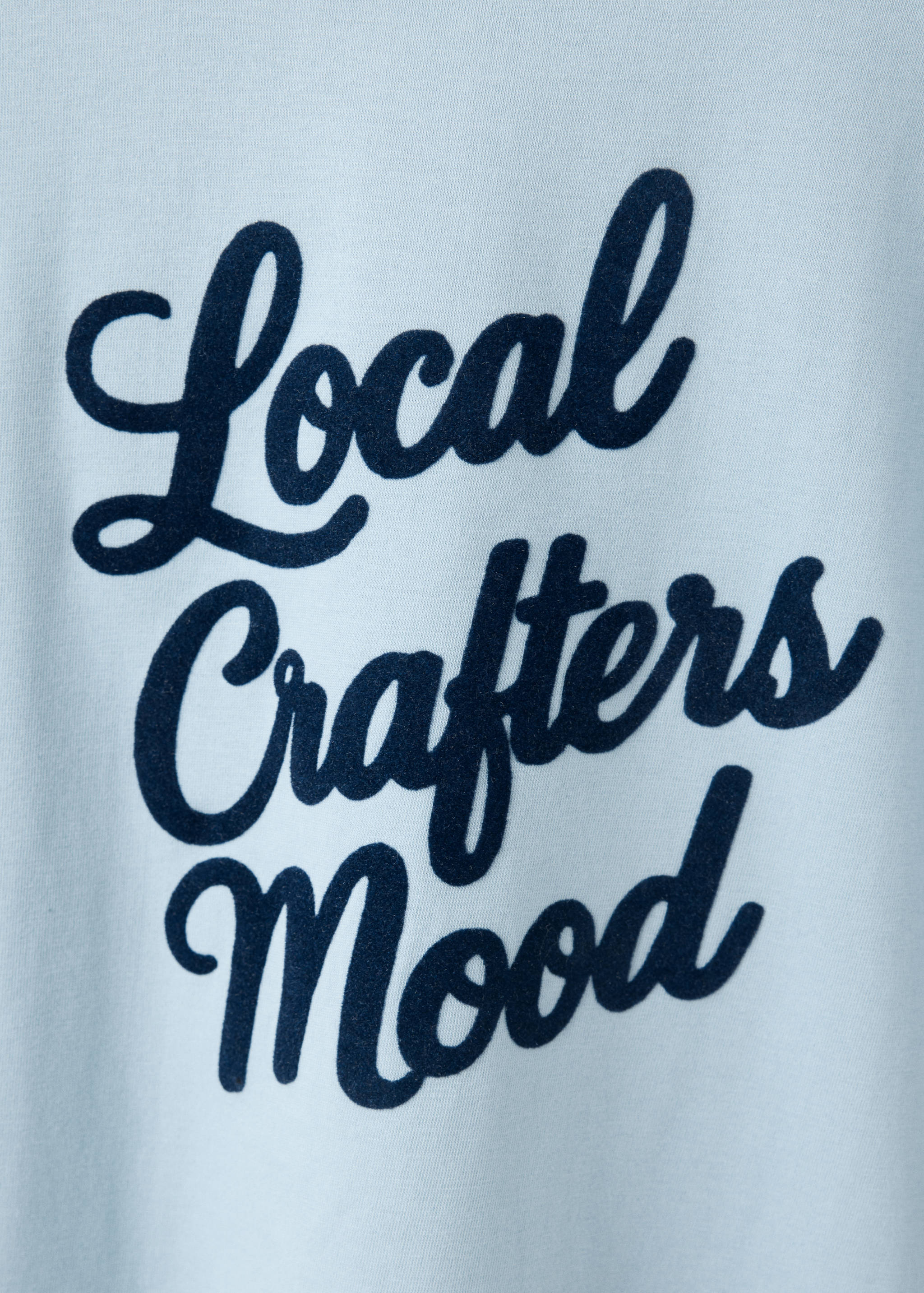 Close-up of a light blue t-shirt with dark text.