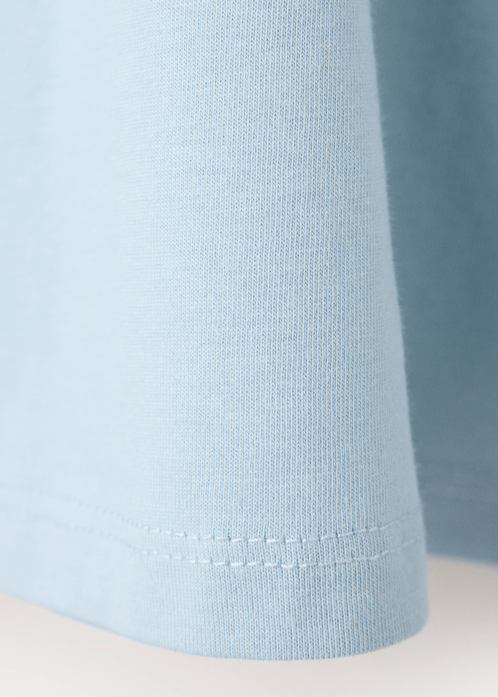 Close-up of the light blue cotton t-shirt fabric and hem.
