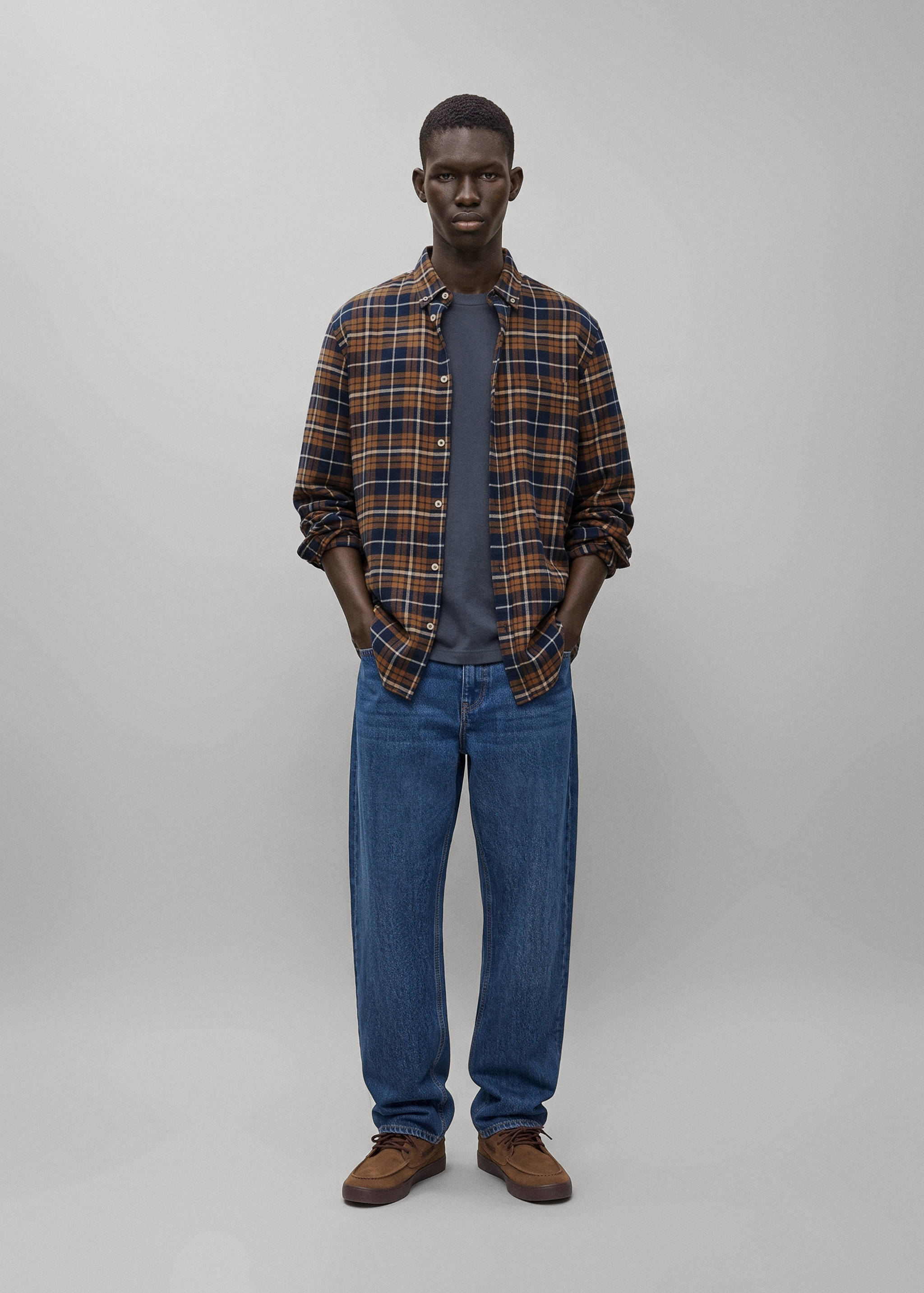 Brown, blue and white plaid shirt worn open over a grey t-shirt.
